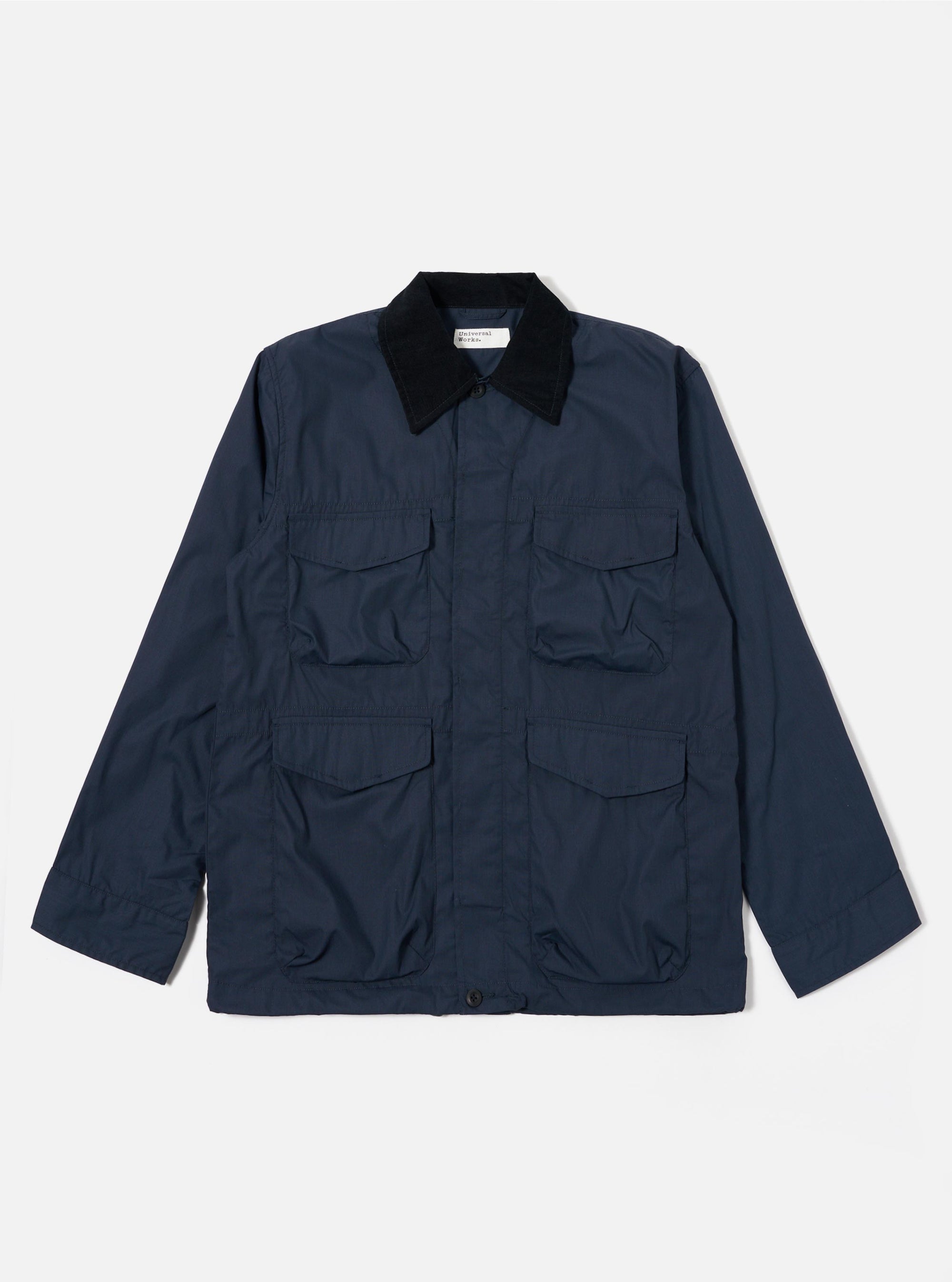 The Navy Recycled Polytech Parachute Field Jacket is shown as a flat lay against a white background. The jacket features a contrasting corduroy collar, a central button-down front, and four large 3D patch pockets with button flaps on the front. The fabric is a smooth, dark navy recycled polytech blend.