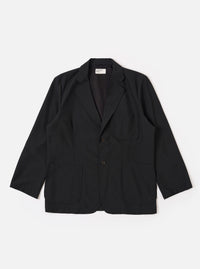 The Black Tropical Suiting Two Button Jacket is shown as a flat lay against a white background. The jacket features a relaxed fit with a long, wide notched lapel, two large lower patch pockets, and a single chest patch pocket. The two-button closure is visible at the center, and the fabric has a smooth, lightweight appearance.