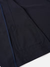 The Navy Tropical Suiting Two Button Jacket is displayed as a flat lay against a plain white background. The jacket features a relaxed, unstructured fit with a two-button front closure and a long, wide notch lapel. Three patch pockets are visible on the front: one at the chest and two larger pockets at the waist. The garment is made from a smooth, lightweight navy blue tropical suiting fabric.