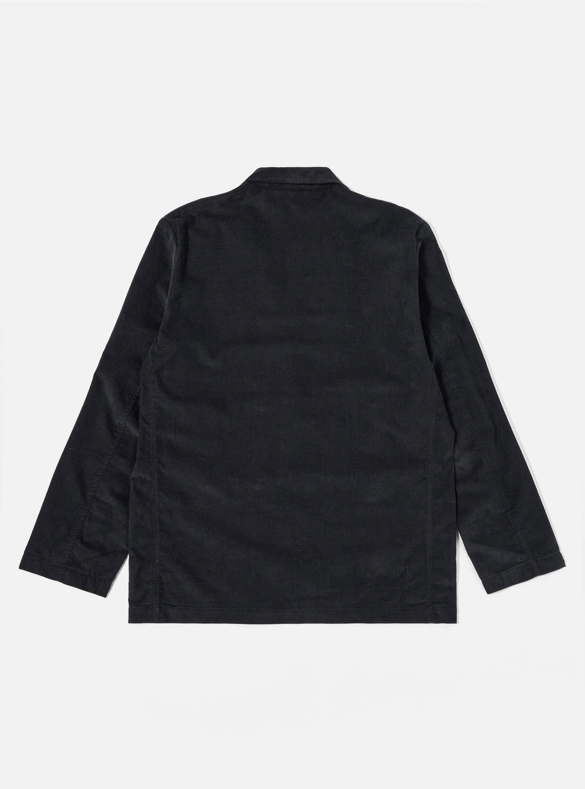 The Black Organic Fine Cord Two Button Jacket is displayed from the back as a flat lay against a plain white background. The image highlights the clean lines of the garment, featuring a central vent at the hem and a structured two-piece sleeve construction. The fine-ribbed texture of the black organic cotton corduroy is visible across the entire surface.