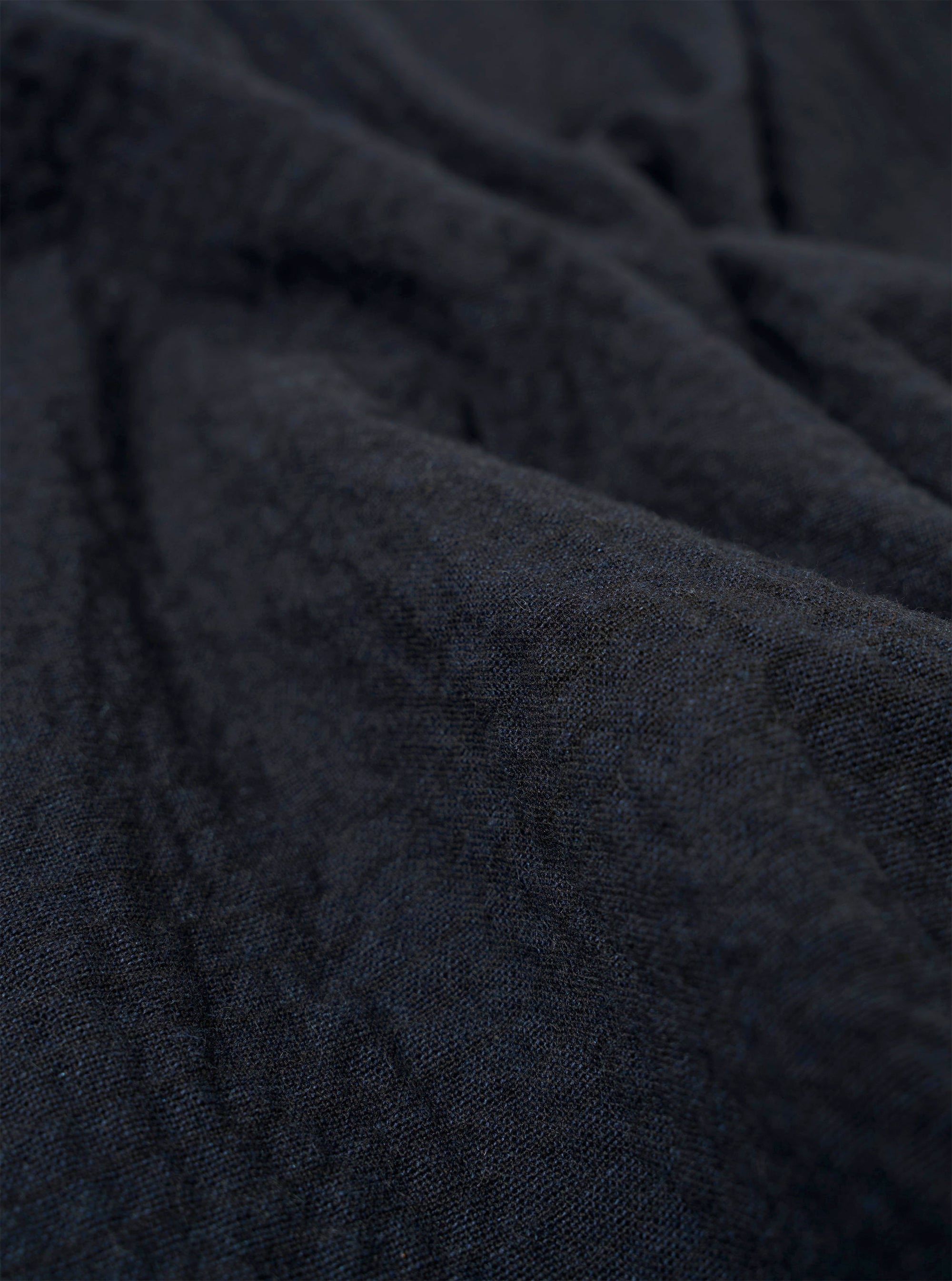 A close-up fabric swatch of the Dark Navy Ospina Cotton Two Button Jacket highlights the deep navy blue color and the distinct puckered texture of the seersucker fabric. The material fills the frame, providing a detailed view of the garment's weave and construction.