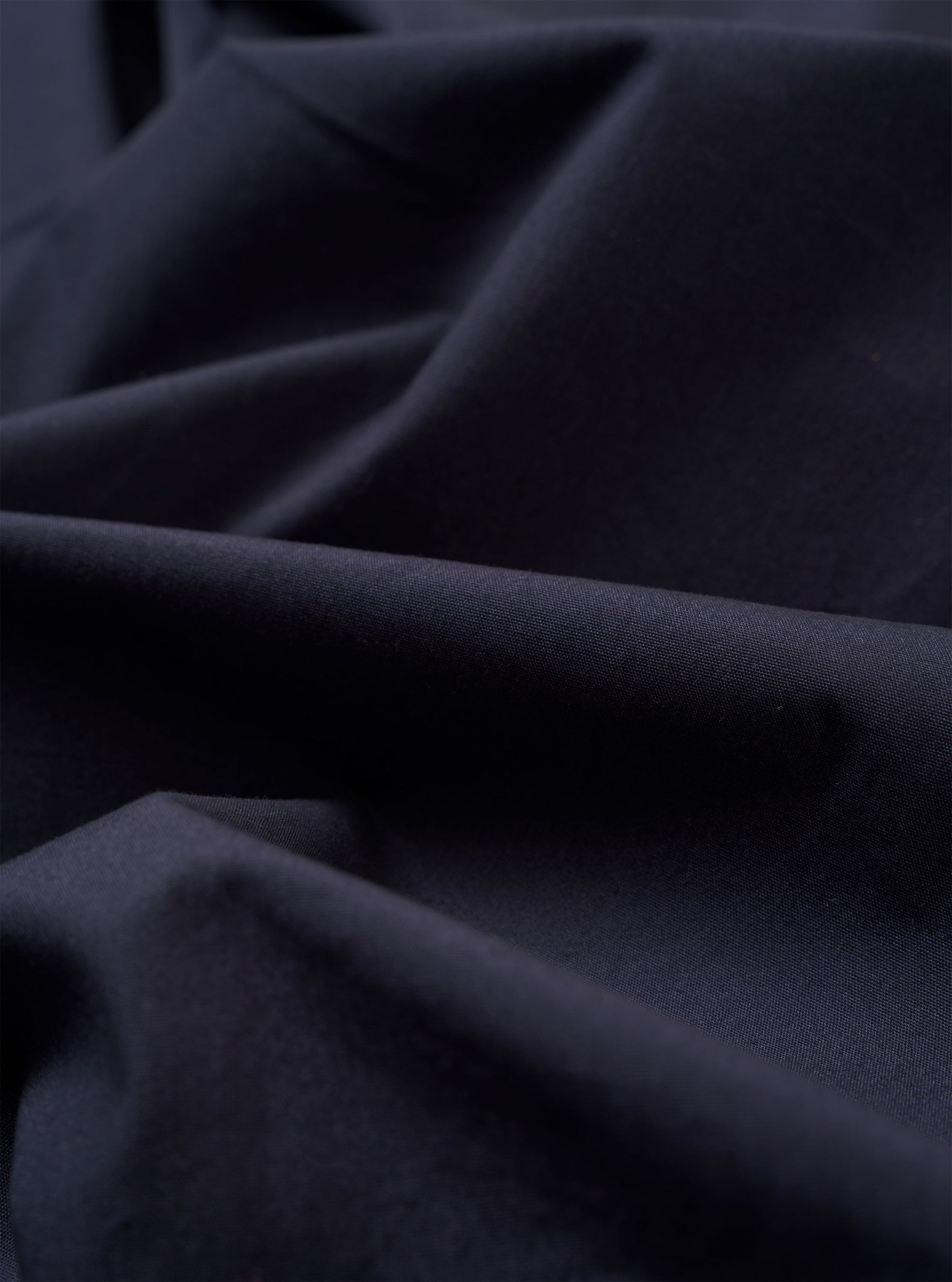 The Navy Peached Poplin Dutch Pant is shown from the back as a flat lay against a white background. The trousers feature two large rear patch pockets and a visible seam running vertically down the center of each leg. The peached poplin fabric has a smooth, matte finish.