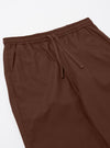 The Brown Peached Poplin Judo Pant is shown from the back as a flat lay against a plain white background. The image highlights the two rear patch pockets, the elasticated waistband with visible stitching, and the relaxed straight-leg cut. The cotton fabric has a soft, matte appearance in a solid brown color.