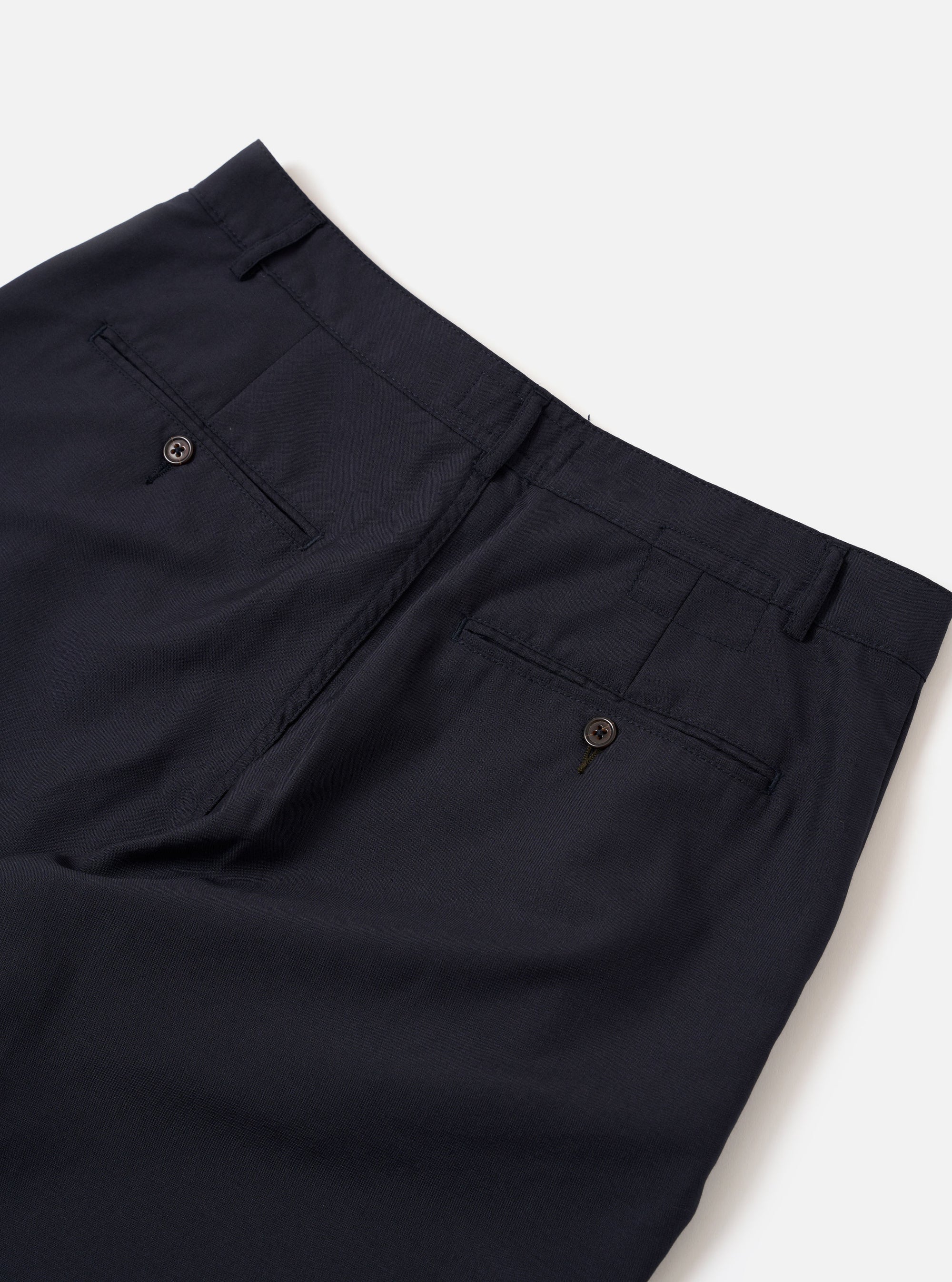 The Navy Tropical Suiting Military Chino is shown from the back as a flat lay against a plain white background. The trousers feature two rear jetted pockets with button closures, belt loops, and a clean, straight-leg silhouette. The navy blue fabric is a smooth tropical suiting with a lightweight appearance.