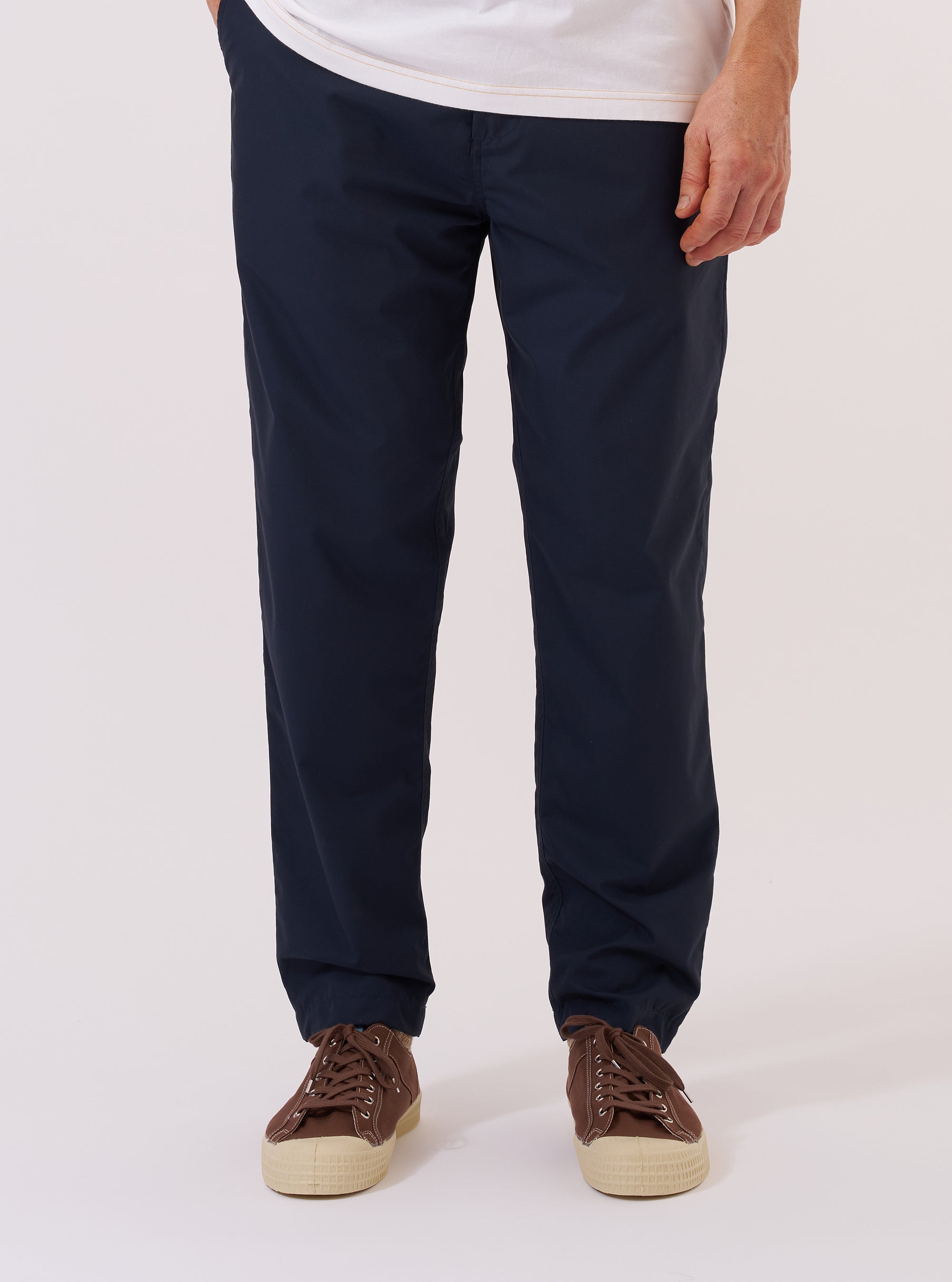 A model wears the Navy Recycled Polytech Military Chino, shown from the waist down against a plain white background. The image highlights the contemporary slim-straight fit of the trousers, which feature a mid-rise, a button fly, and two front pockets. The dark navy fabric is a smooth recycled polyester and cotton blend. The model is wearing the chinos with a light-colored shirt and dark footwear.