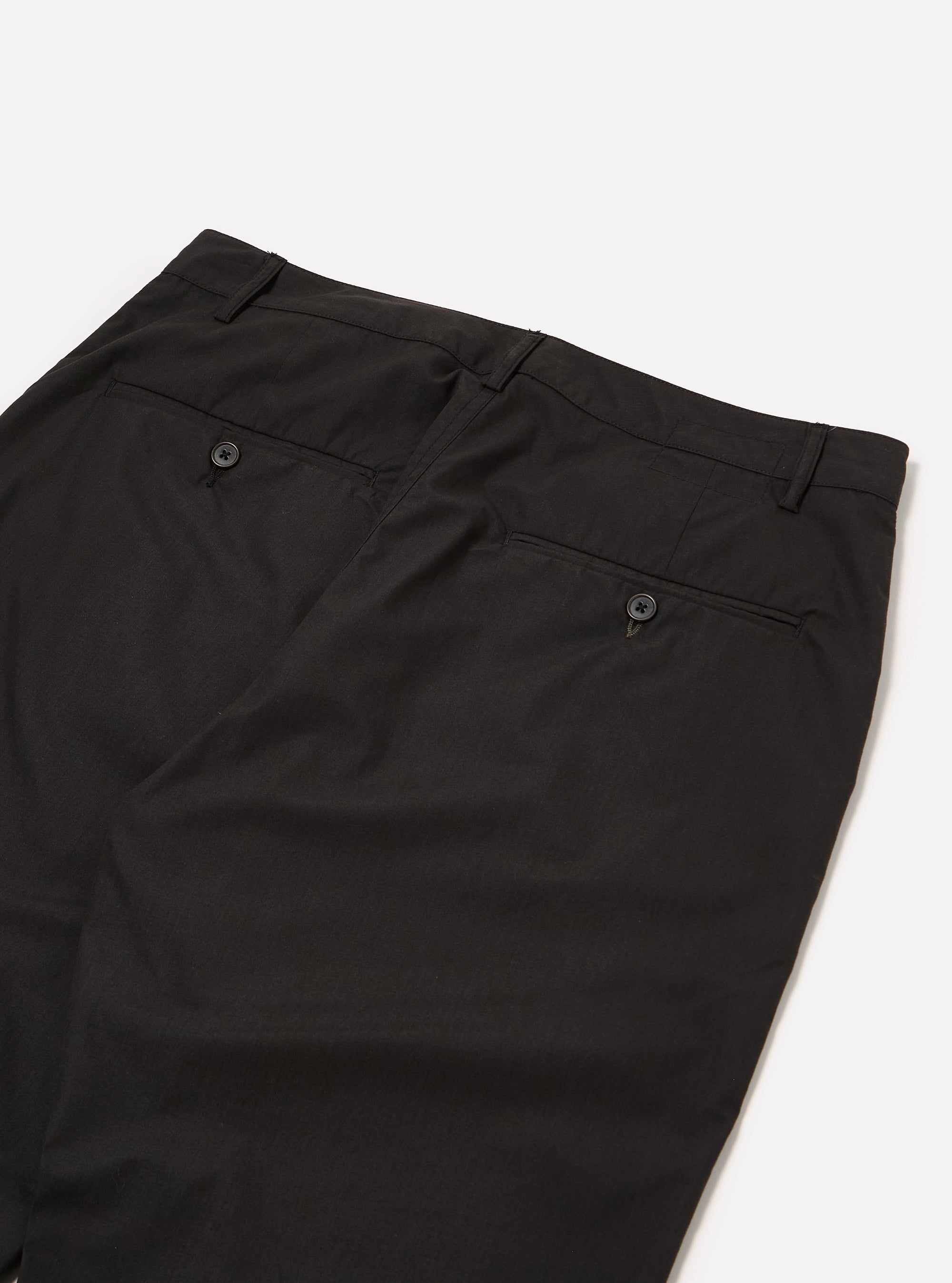 The Black Recycled Polytech Military Chino is shown from a rear angle as a flat lay against a plain white background. The image highlights the two rear jetted pockets with button closures and the clean, straight-leg construction of the black technical fabric.