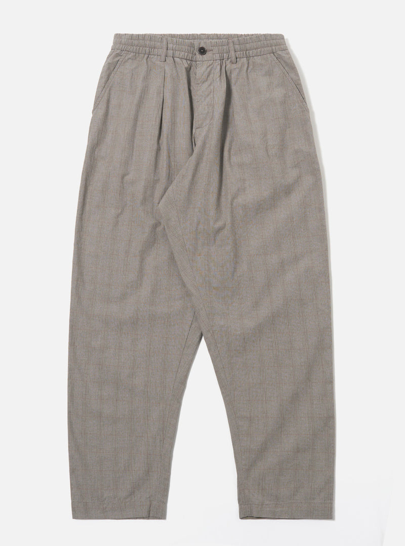 The Grey Brown Wales Glen Check Pleated Track Pant is shown as a flat lay against a plain white background. The trousers feature a single front pleat, an elasticated waistband with a matching drawstring, and two side slant pockets. The cotton fabric showcases a detailed grey and brown glen check pattern throughout the loose, tapered silhouette.