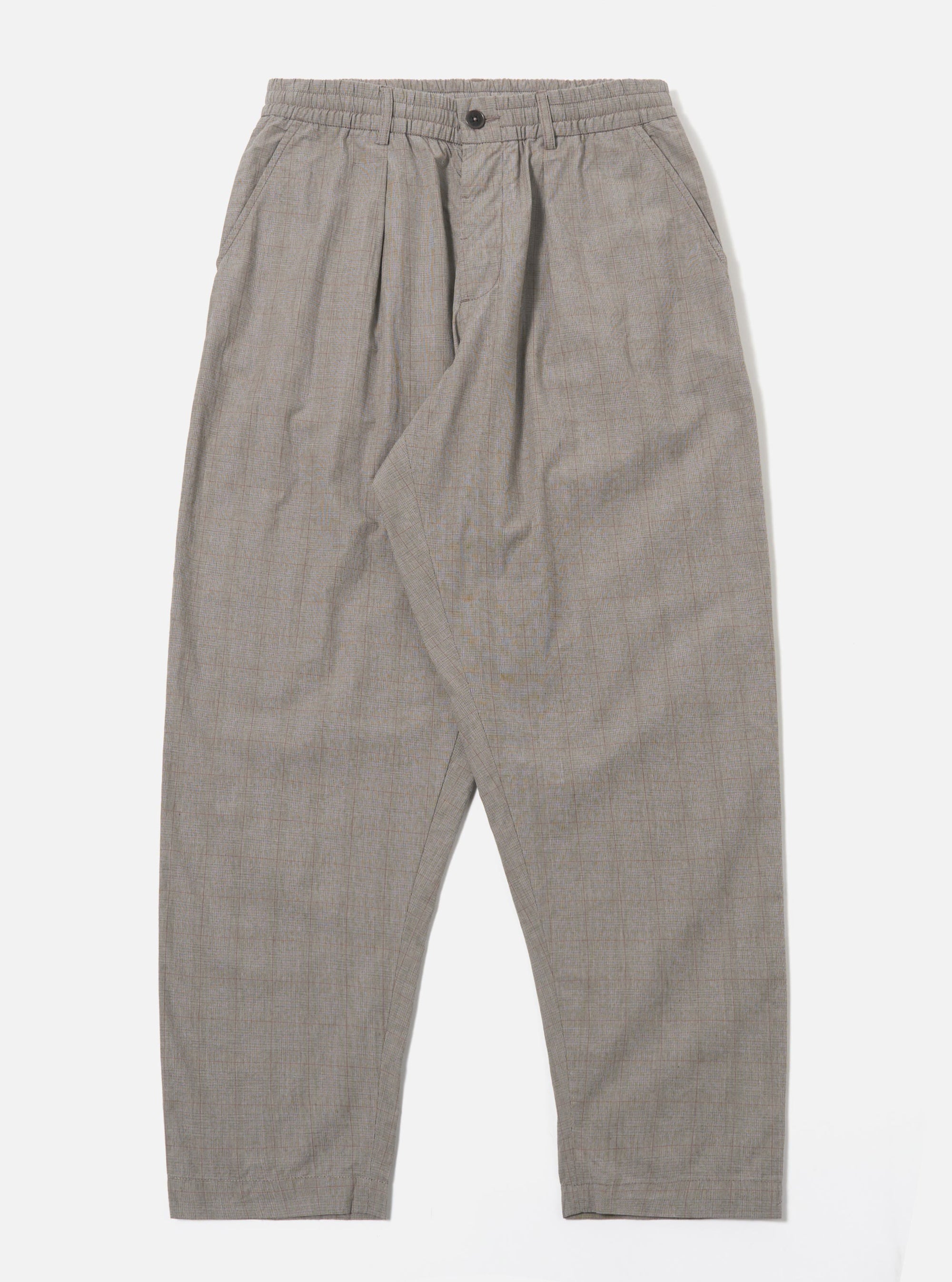 The Grey Brown Wales Glen Check Pleated Track Pant is shown as a flat lay against a plain white background. The trousers feature a single front pleat, an elasticated waistband with a matching drawstring, and two side slant pockets. The cotton fabric showcases a detailed grey and brown glen check pattern throughout the loose, tapered silhouette.