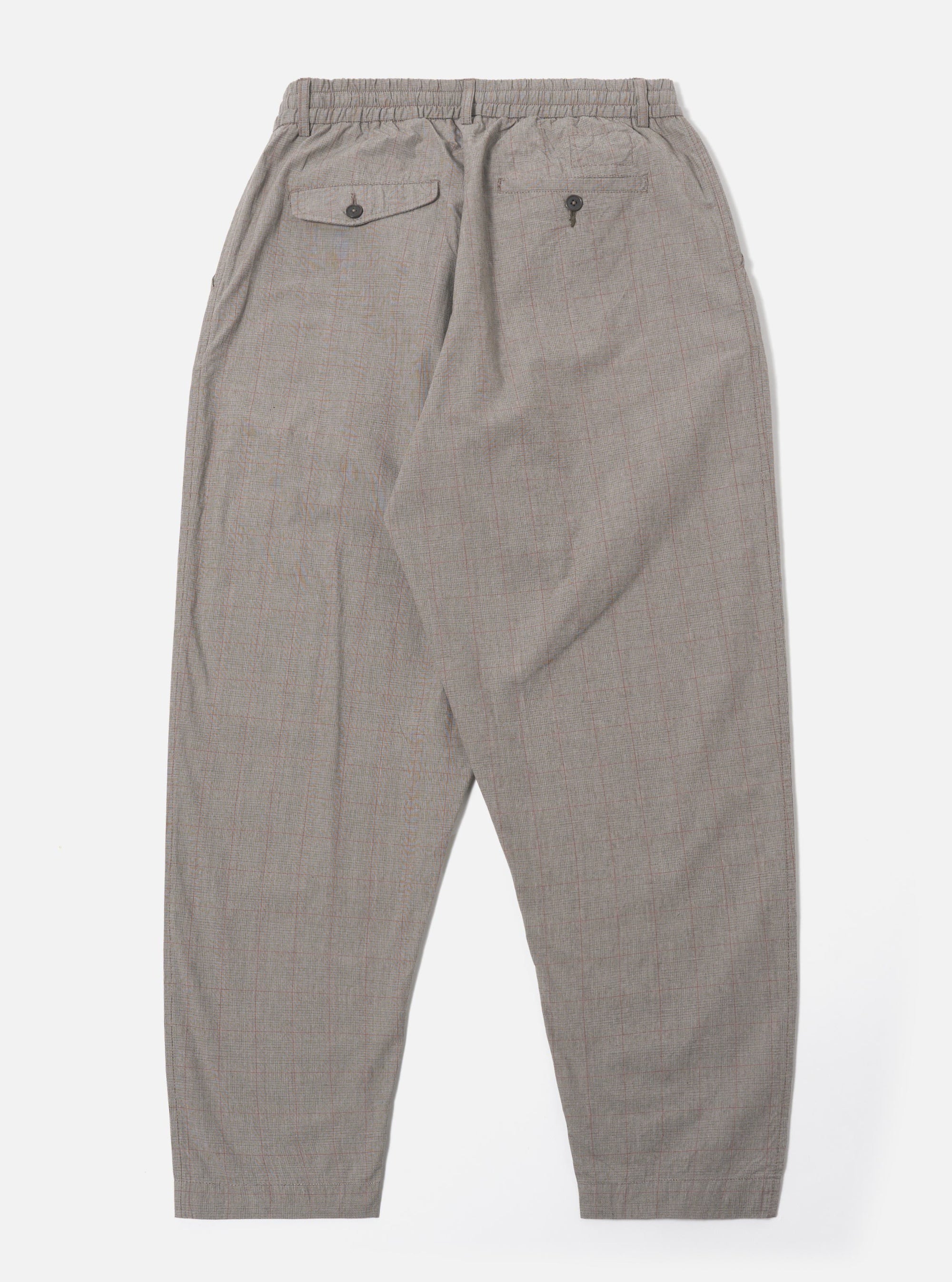 The Grey Brown Wales Glen Check Pleated Track Pant is shown from the back as a flat lay against a plain white background. The image highlights the elasticated waistband and a single rear patch pocket with a buttoned flap. The cotton fabric features a detailed grey and brown glen check pattern and a tapered leg silhouette.