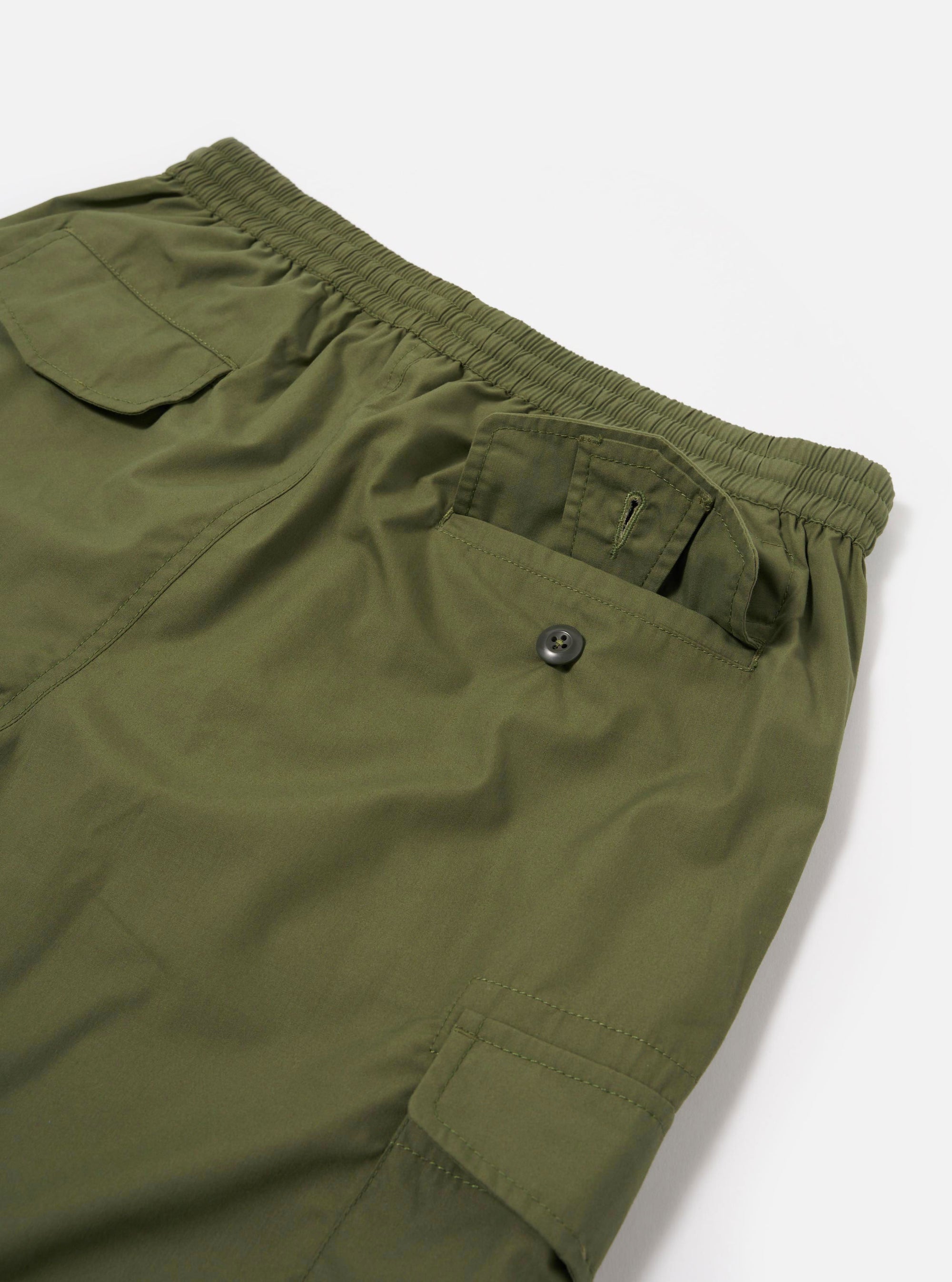 The Olive Recycled Polytech Parachute Short is shown from the back as a flat lay against a plain white background. The image highlights the two rear patch pockets with buttoned flaps, an elasticated waistband, and the smooth olive green recycled polytech fabric.