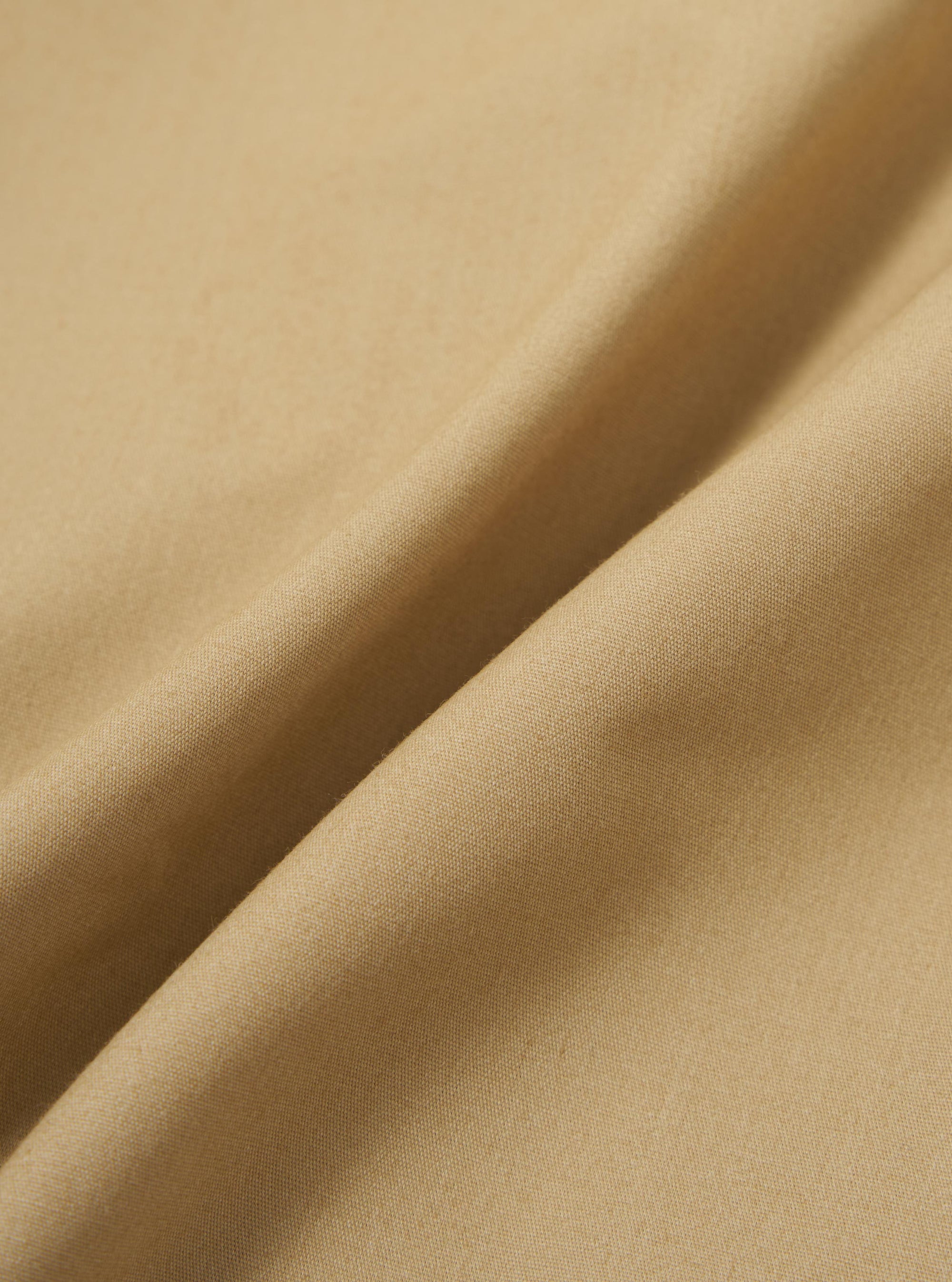 A close-up fabric swatch of the Sand Recycled Polytech Parachute Short is shown, highlighting the fine, technical weave and light beige color of the material.
