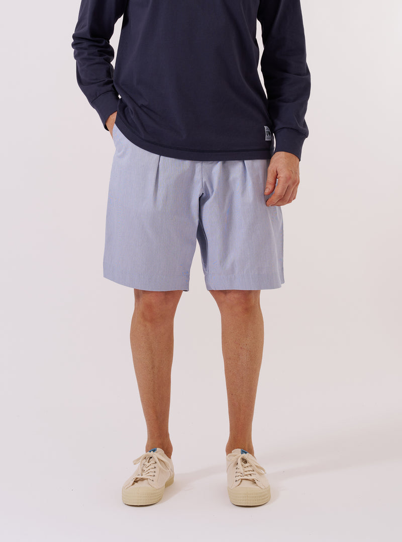 The Navy Kennedy Stripe Pleated Track Short is displayed as a flat lay against a plain white background. The shorts feature a vertical white pinstripe pattern on a navy base, an elasticated waistband with a drawstring, and a single pleat on each leg. Two side pockets are visible, and the garment has a relaxed fit.