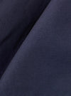 A close-up fabric swatch of the Navy Peached Poplin Pleated Track Short highlights the smooth, matte texture and deep navy blue color of the peached poplin material. The fabric fills the frame, showcasing its fine weave and soft finish.