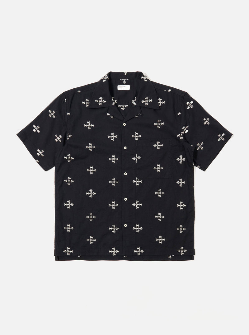 The Black Embroidered Diamond Camp Shirt is shown as a flat lay against a white background. The shirt features a camp collar, short sleeves, a full button-down front with tonal buttons, and a single chest pocket on the left side. A subtle, repeating diamond pattern is embroidered throughout the black fabric.