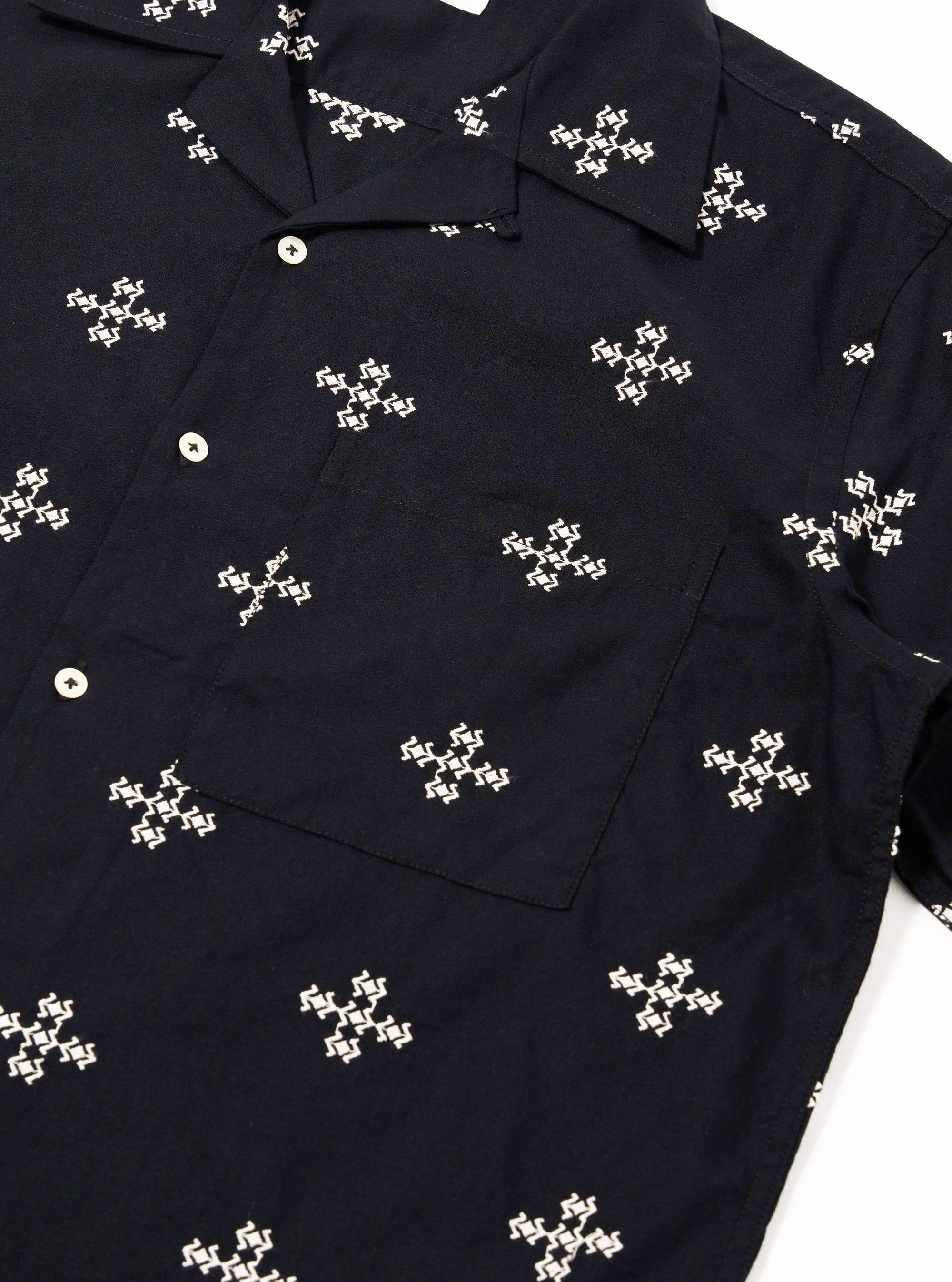 The Black Embroidered Diamond Camp Shirt is shown from a rear angle as a flat lay against a plain white background. The image highlights the back of the shirt, showcasing the straight hem, short sleeves, and the continued pattern of the embroidered diamond design across the shoulders and back panel.