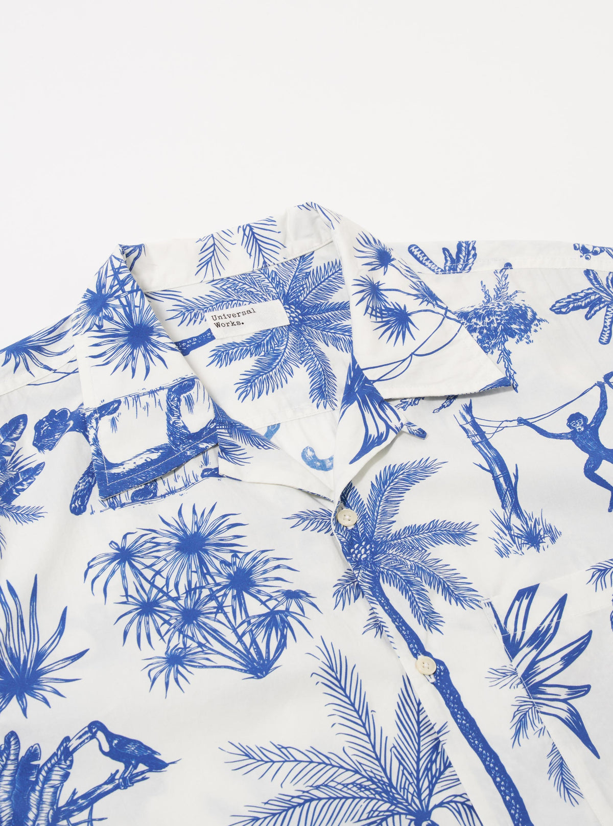 The White Jungle Toile Poplin Camp Shirt is shown from the back as a flat lay against a plain white background. The shirt features a straight hem, a simple back yoke, and a continuous jungle toile print with dark botanical and animal illustrations on an ecru base. The fabric appears lightweight with a smooth poplin texture.