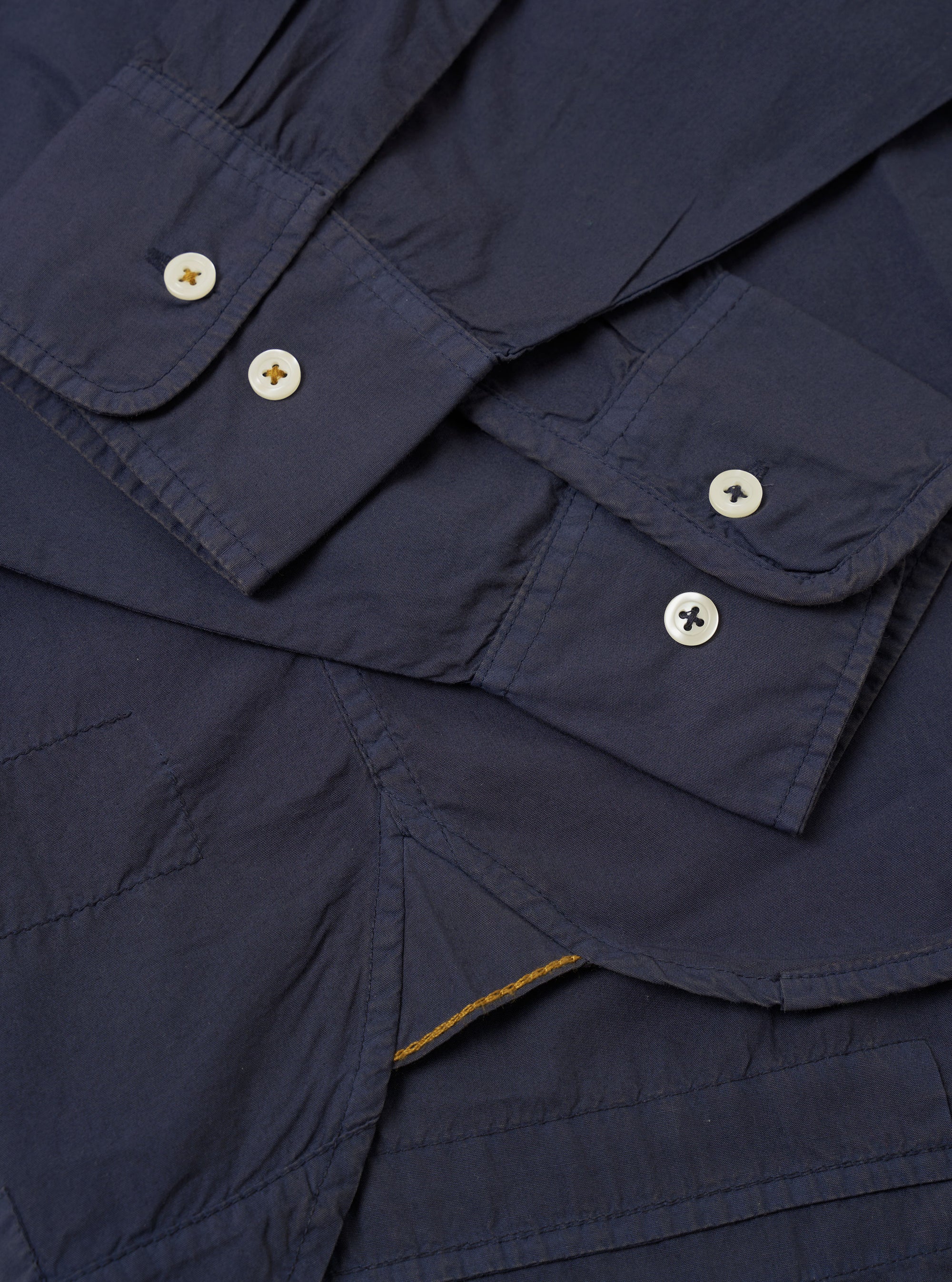 The Navy Poplin Patched Lazy Day Shirt is shown in a detail view as a flat lay against a plain white background. The image highlights the smooth texture of the navy blue cotton poplin fabric and the construction of the pointed collar and top button.