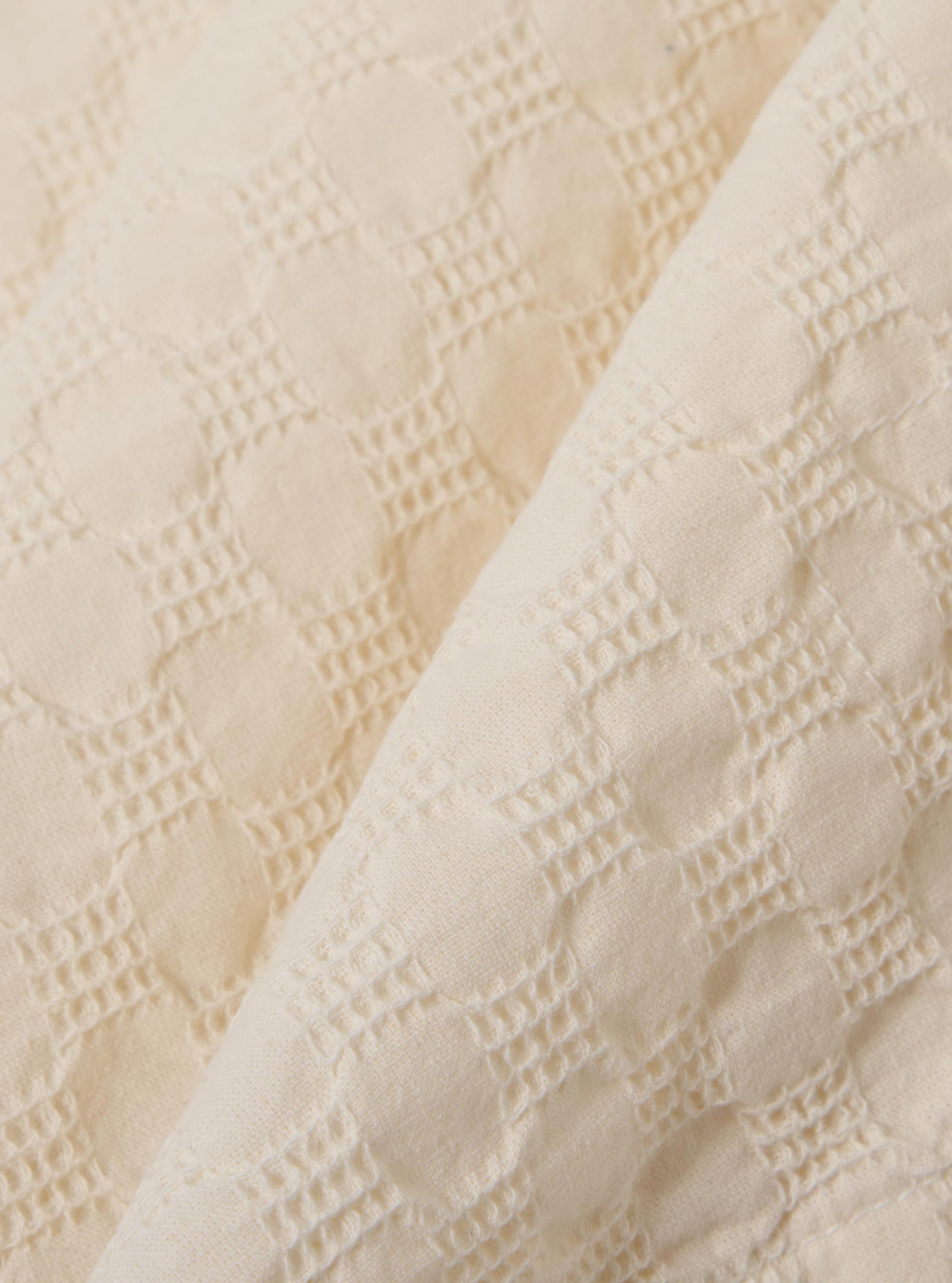 The Ecru Dot Waffle Road Shirt is shown as a close-up fabric swatch. The image highlights the detailed dot waffle texture of the 100% ecru cotton material, which features a rounded seersucker-like weave.