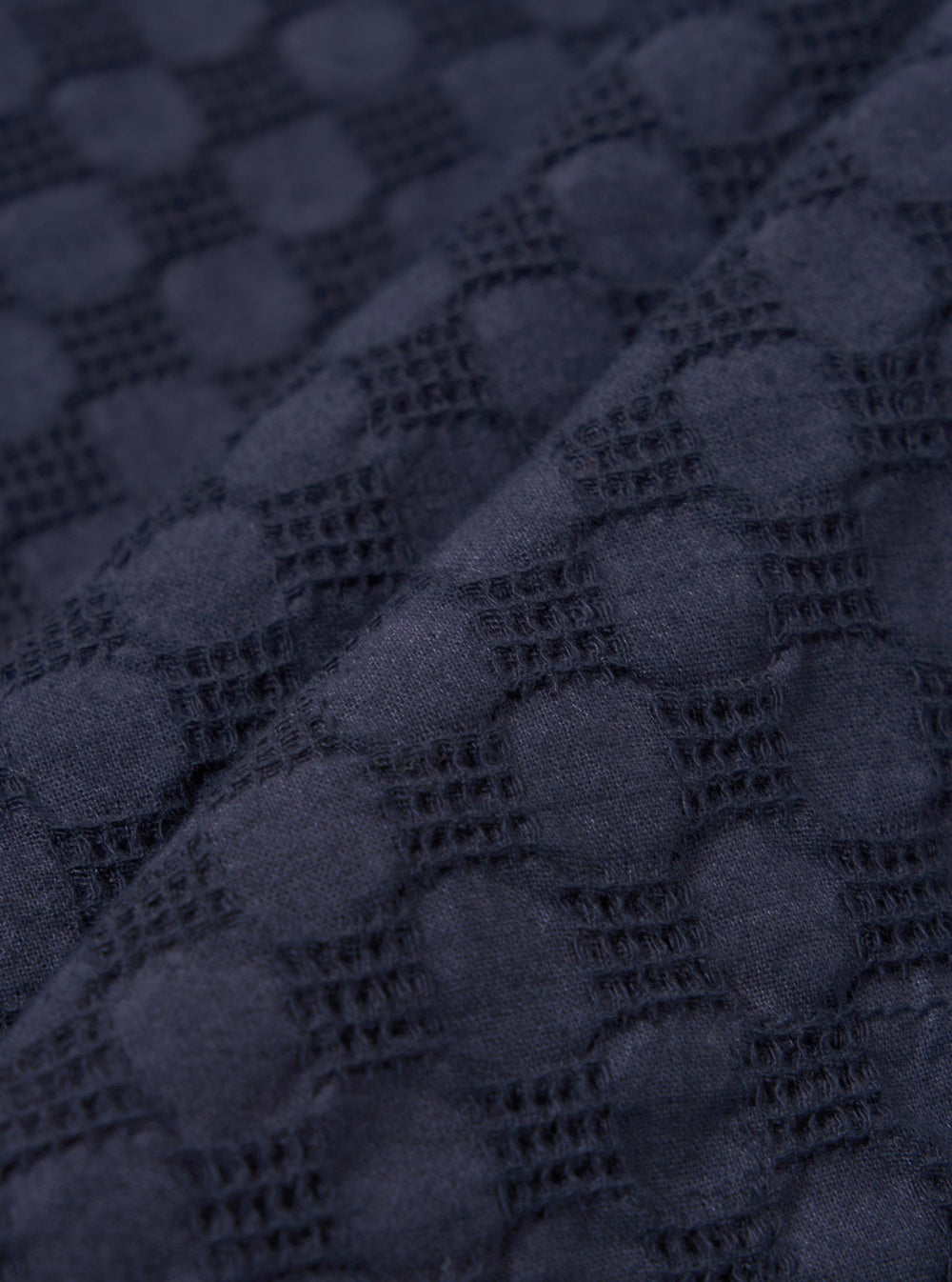 A close-up fabric swatch of the Navy Dot Waffle Road Shirt is shown, highlighting the deep navy blue color and the intricate waffle-weave texture with a subtle dot pattern. The textured cotton fabric fills the frame.