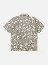 The Ecru/Black Kantha Flower Road Shirt is shown from the back as a flat lay against a plain white background. The shirt features an all-over floral pattern created with traditional black Kantha embroidery on an ecru cotton base. The image highlights the straight hem, short sleeves, and the intricate, textured detail of the artisanal hand-stitched embroidery across the entire back panel.