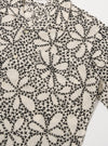 The Ecru/Black Kantha Flower Road Shirt is shown from the back as a flat lay against a plain white background. The short-sleeve shirt features a straight hem and highlights the intricate black floral Kantha embroidery across the ecru cotton fabric.