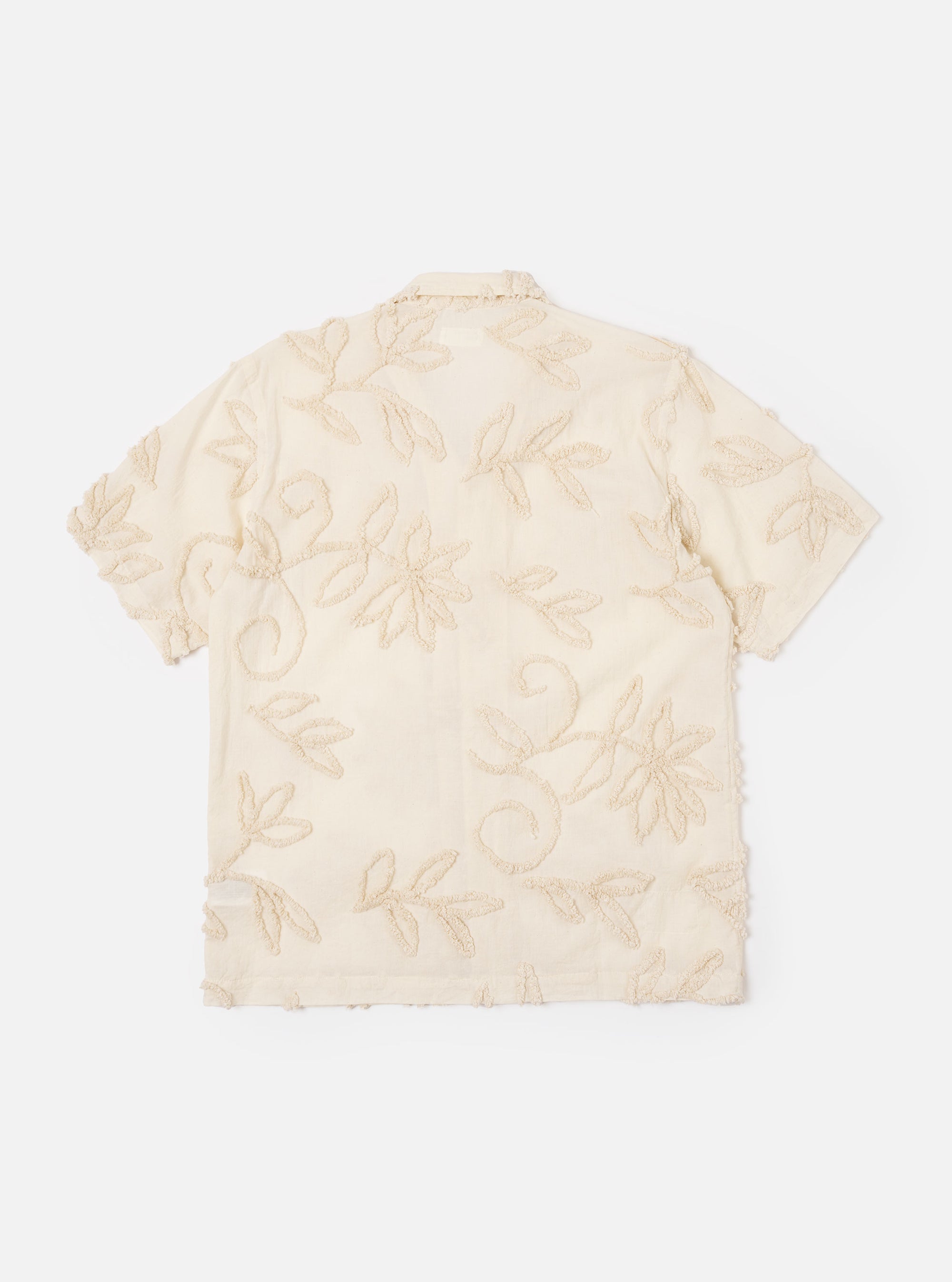 The Ecru 3D Flower Road Shirt is shown as a flat lay against a white background. The short-sleeve shirt features a camp collar, a single chest patch pocket, and a straight hem. The fabric is a light ecru color with a textured 3D floral pattern.