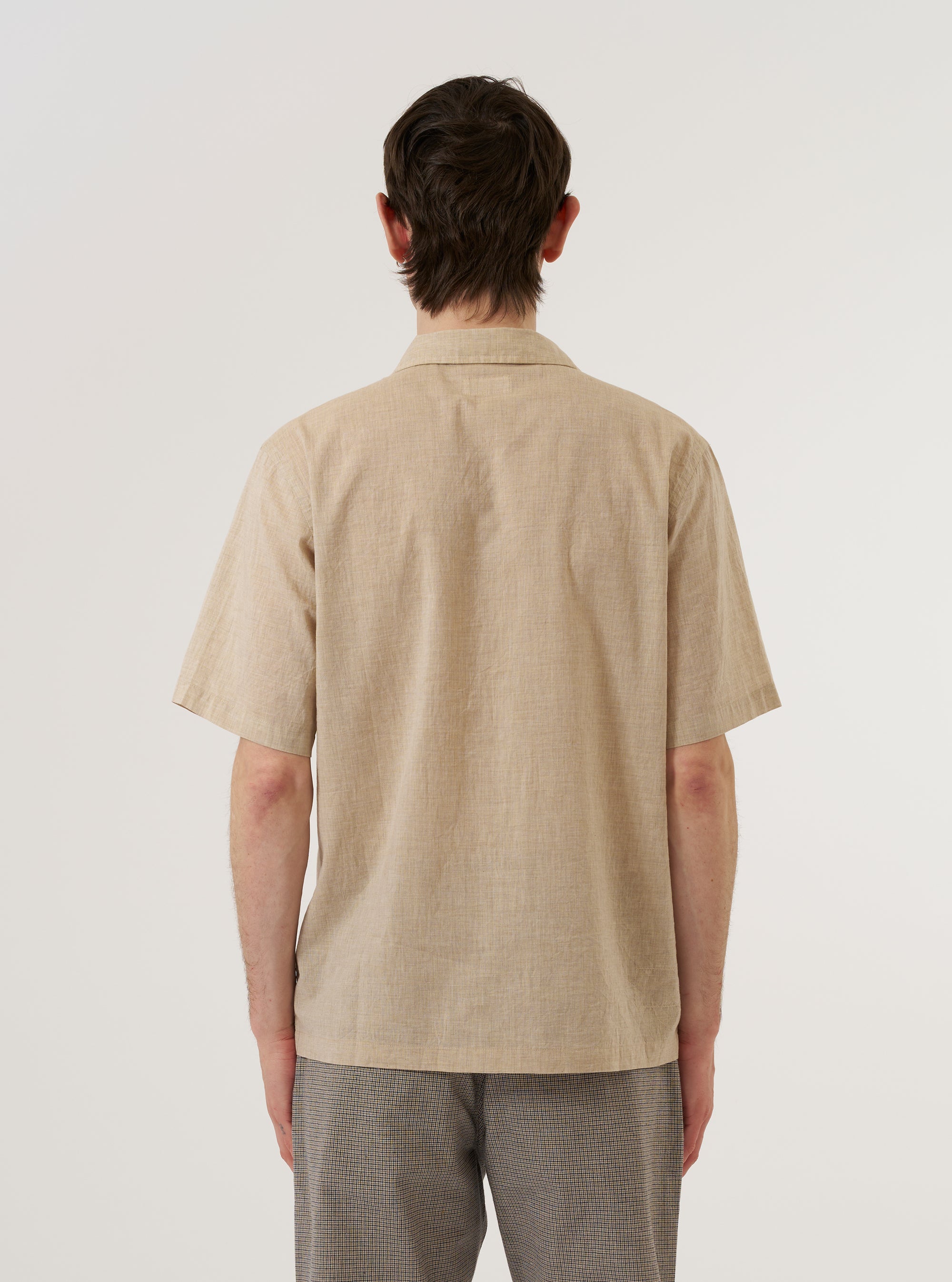 A model wears the Beige Fine Organic Cotton Sal Road Shirt, shown from the back against a plain white background. The shirt features a relaxed fit, short sleeves, and a straight hem. The light beige fabric is made from fine organic cotton and has a smooth appearance.