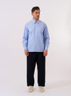The Sky Fil A Fil Square Pocket Shirt is shown as a flat lay against a white background. The shirt features a full button-down front, a classic collar, and a prominent oversized square pocket on the left chest. The fabric is a sky blue fil-a-fil weave with a subtle texture.