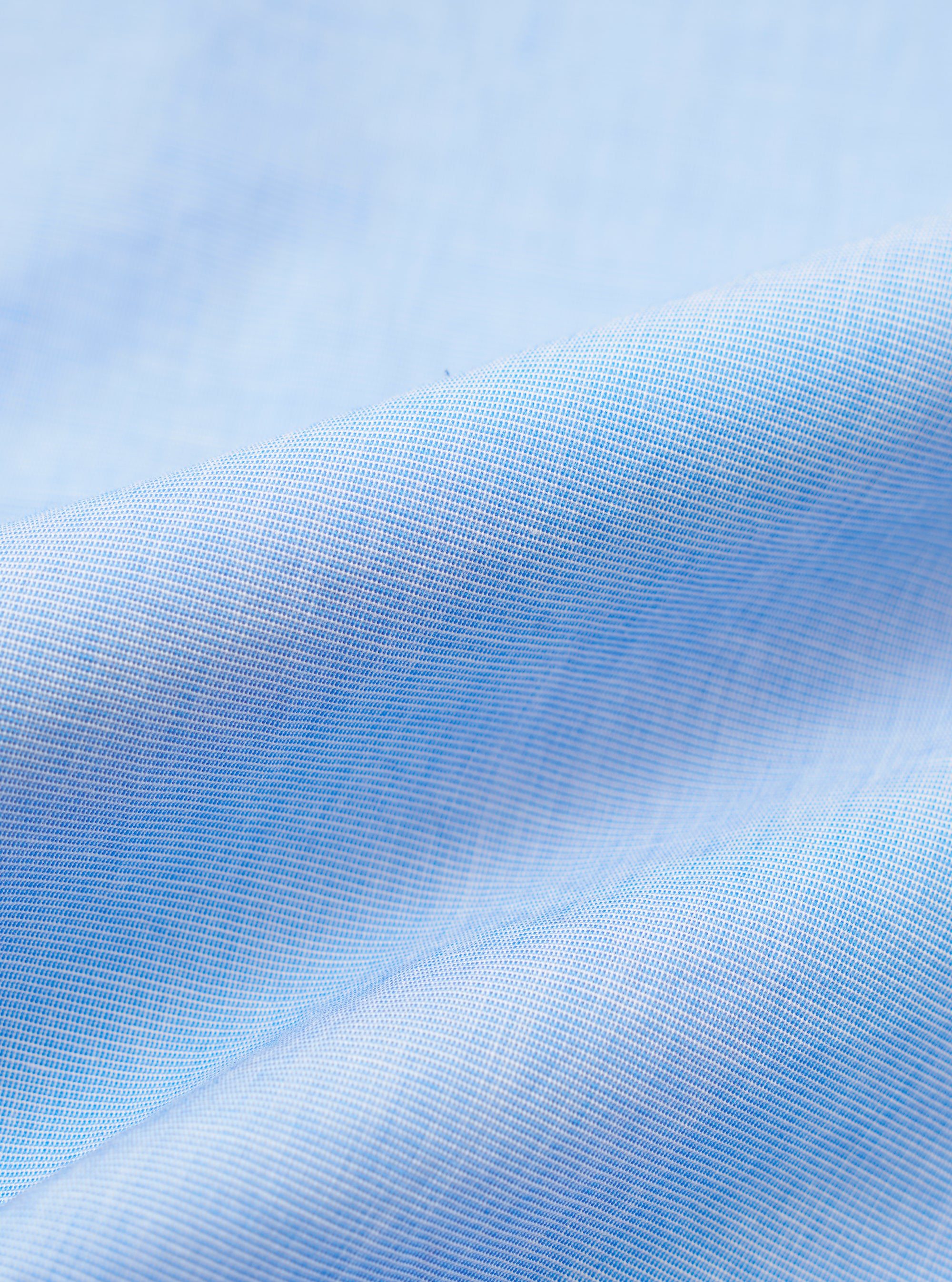 A close-up fabric swatch of the Sky Fil A Fil Square Pocket Shirt shows a fine, textured weave in a pale blue color. The fabric has a subtle, heathered appearance typical of fil-a-fil material.