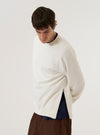 A model wears the Ecru Brush Back Sweat Billy Sweat, shown from a three-quarter rear angle against a plain, neutral background. The sweatshirt features a classic crew neckline, long sleeves with ribbed cuffs, and a ribbed hem. The ecru-colored cotton fabric has a soft, brushed-back appearance and a relaxed silhouette. No mannequin is present in the image.