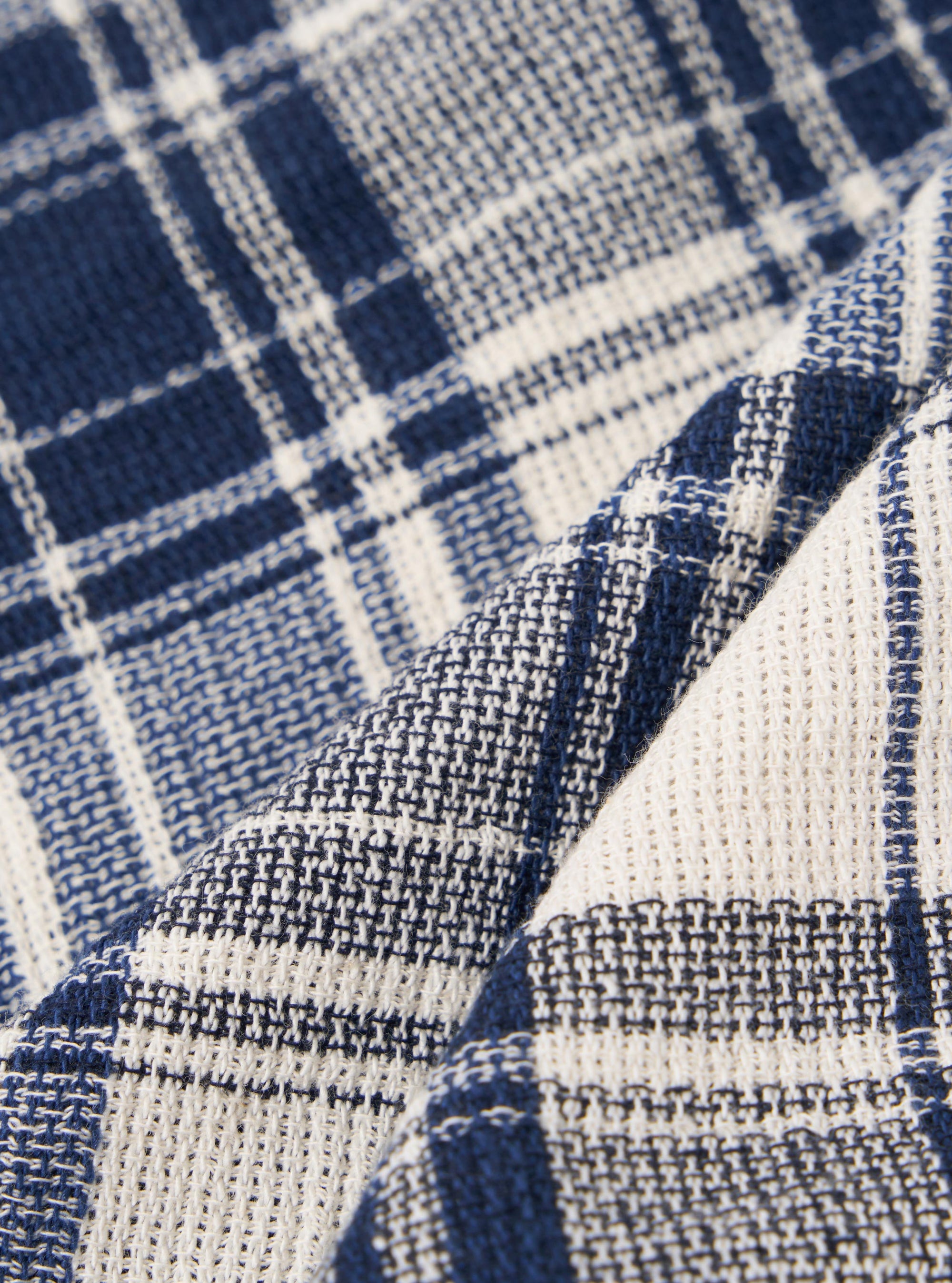 A close-up swatch image of the Navy Texture Plaid Scout Scarf fabric displays a detailed view of the textile. The image features a textured plaid pattern with a navy blue base and intersecting lines. The fabric has a visible weave and a soft, matte finish.
