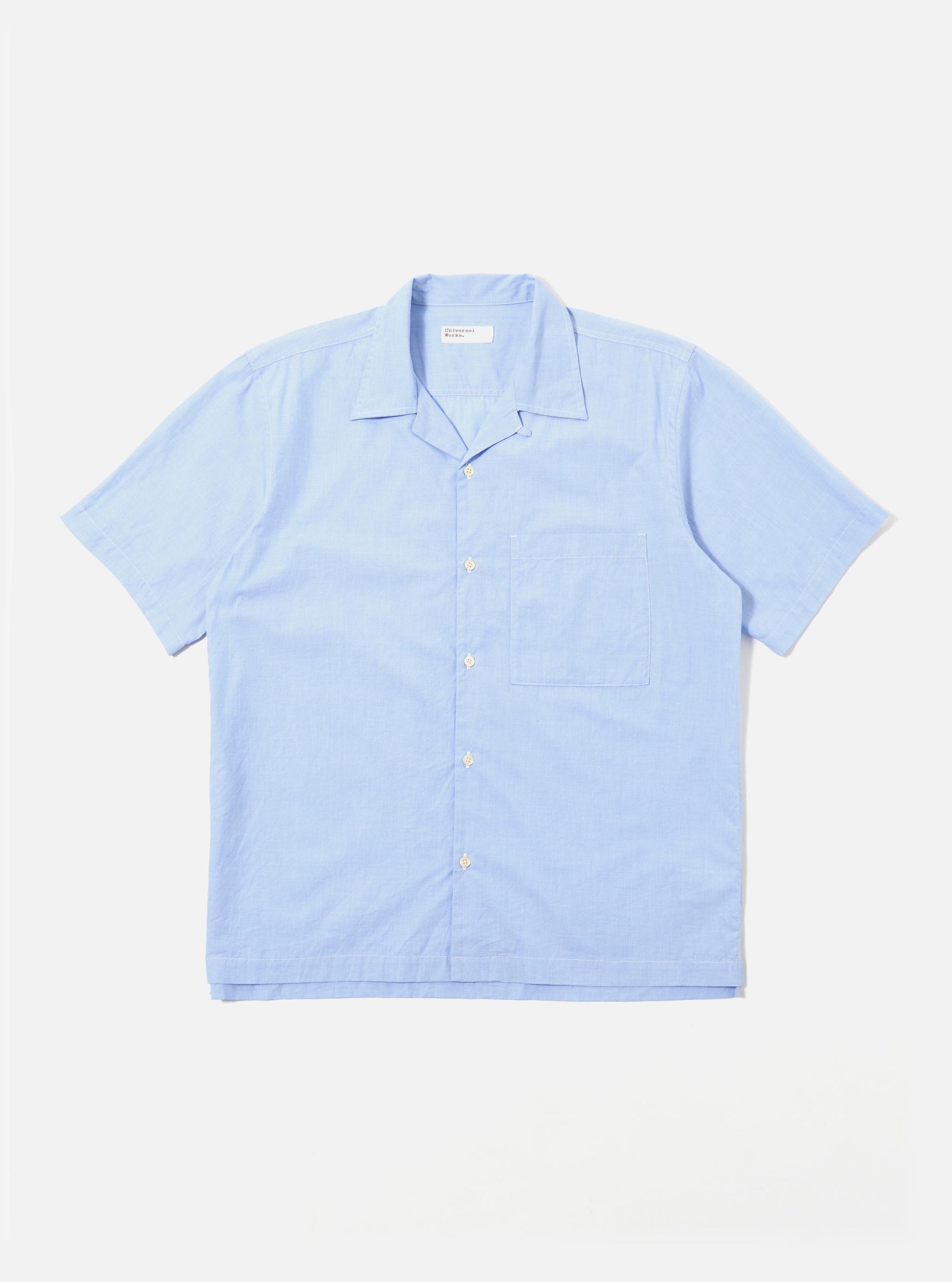 The Sky Fil A Fil Camp Shirt is shown as a flat lay against a white background. The short-sleeve shirt features a relaxed camp collar, a central six-button closure, and a single patch pocket on the left chest. The light blue cotton fabric has a fine, multi-tonal fil-a-fil weave.