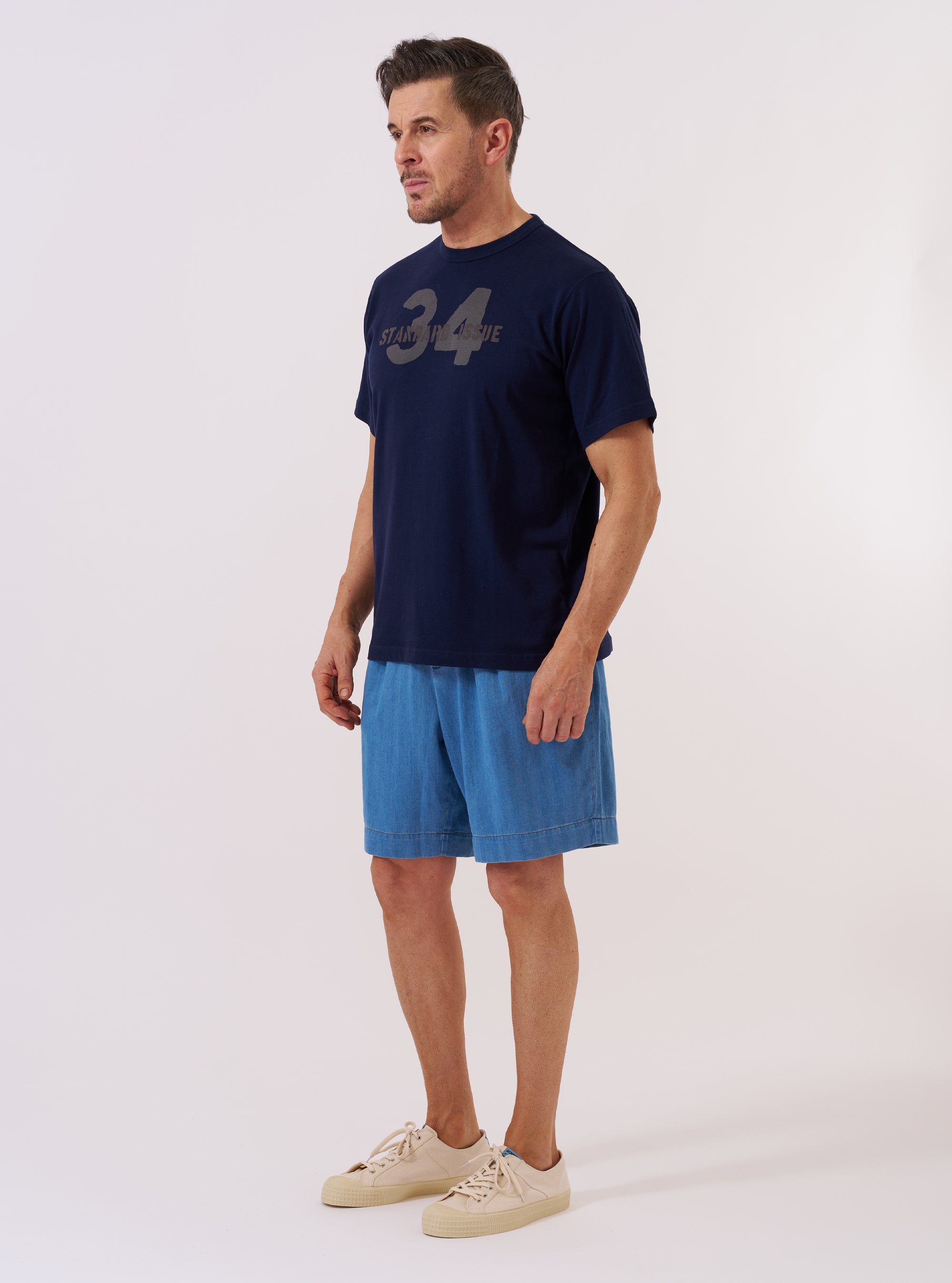 The Navy Single Jersey 34 Printed Core Tee is shown as a flat lay against a plain white background. The t-shirt features a crew neckline, short sleeves, and a white graphic print on the center chest. The fabric is a smooth navy blue cotton jersey.