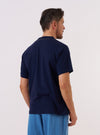 A model wears the Navy Single Jersey 34 Printed Core Tee, shown from a rear angle against a plain white background. The t-shirt features short sleeves and a classic crew neckline, crafted from a navy blue single jersey cotton. The image focuses on the relaxed fit and the clean finish of the garment's back and sleeves.