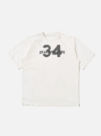 The Ecru Single Jersey 34 Printed Core Tee is shown as a flat lay against a white background. The short-sleeved t-shirt features a ribbed crew neck and a graphic print on the chest. The garment is made from a solid ecru-colored cotton jersey.