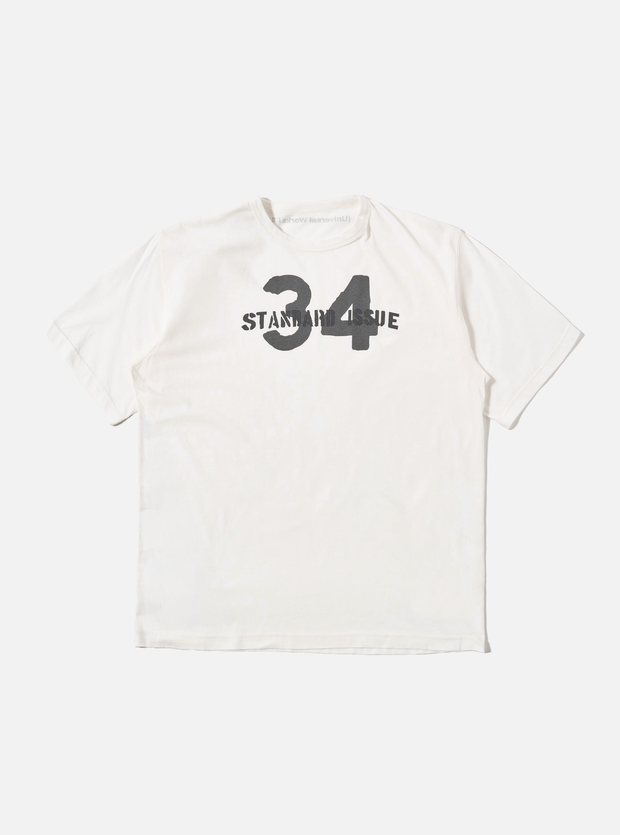 The Ecru Single Jersey 34 Printed Core Tee is shown as a flat lay against a white background. The short-sleeved t-shirt features a ribbed crew neck and a graphic print on the chest. The garment is made from a solid ecru-colored cotton jersey.