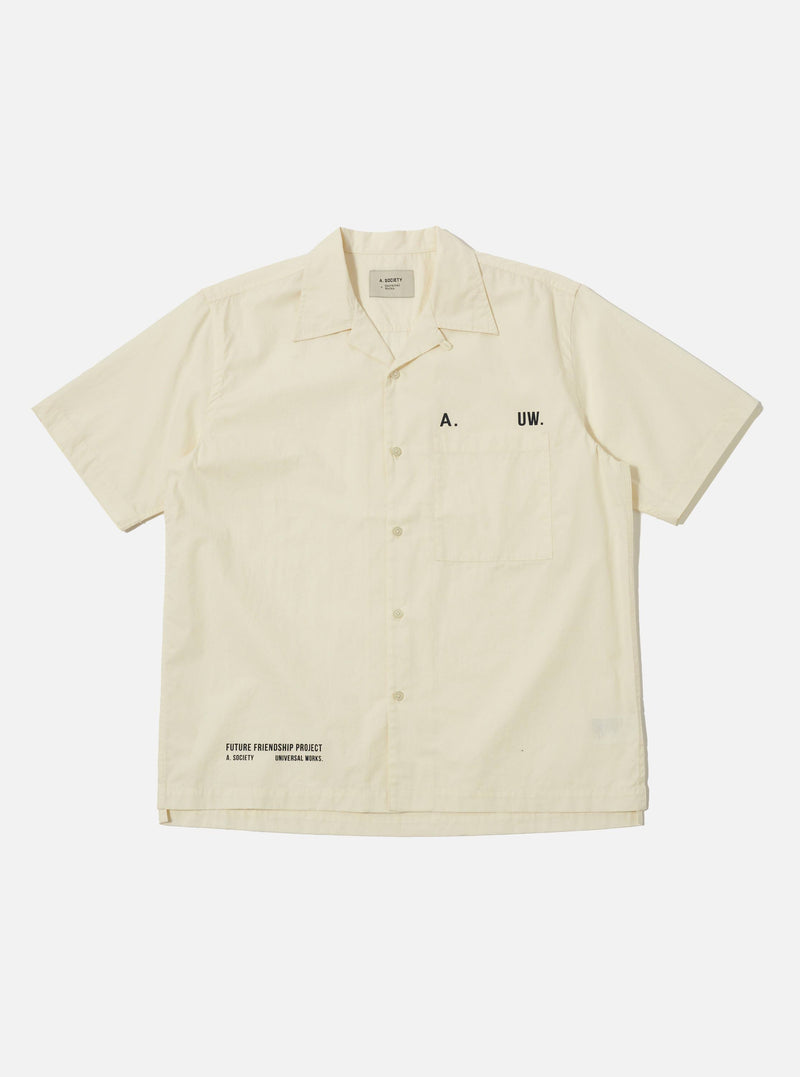 The A. SOCIETY x Universal Works Ecru Broadcloth Camp Shirt is laid flat on a white background. The shirt is a light cream color with short sleeves and a button-up front.