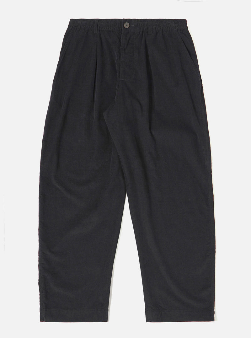 The Black Organic Fine Cord Oxford Pant is shown as a flat lay against a white background. The trousers feature a wide leg with a slight taper, a single pleat front, and an elasticated waistband with a drawstring. The garment is made from a black organic fine-wale cotton corduroy.