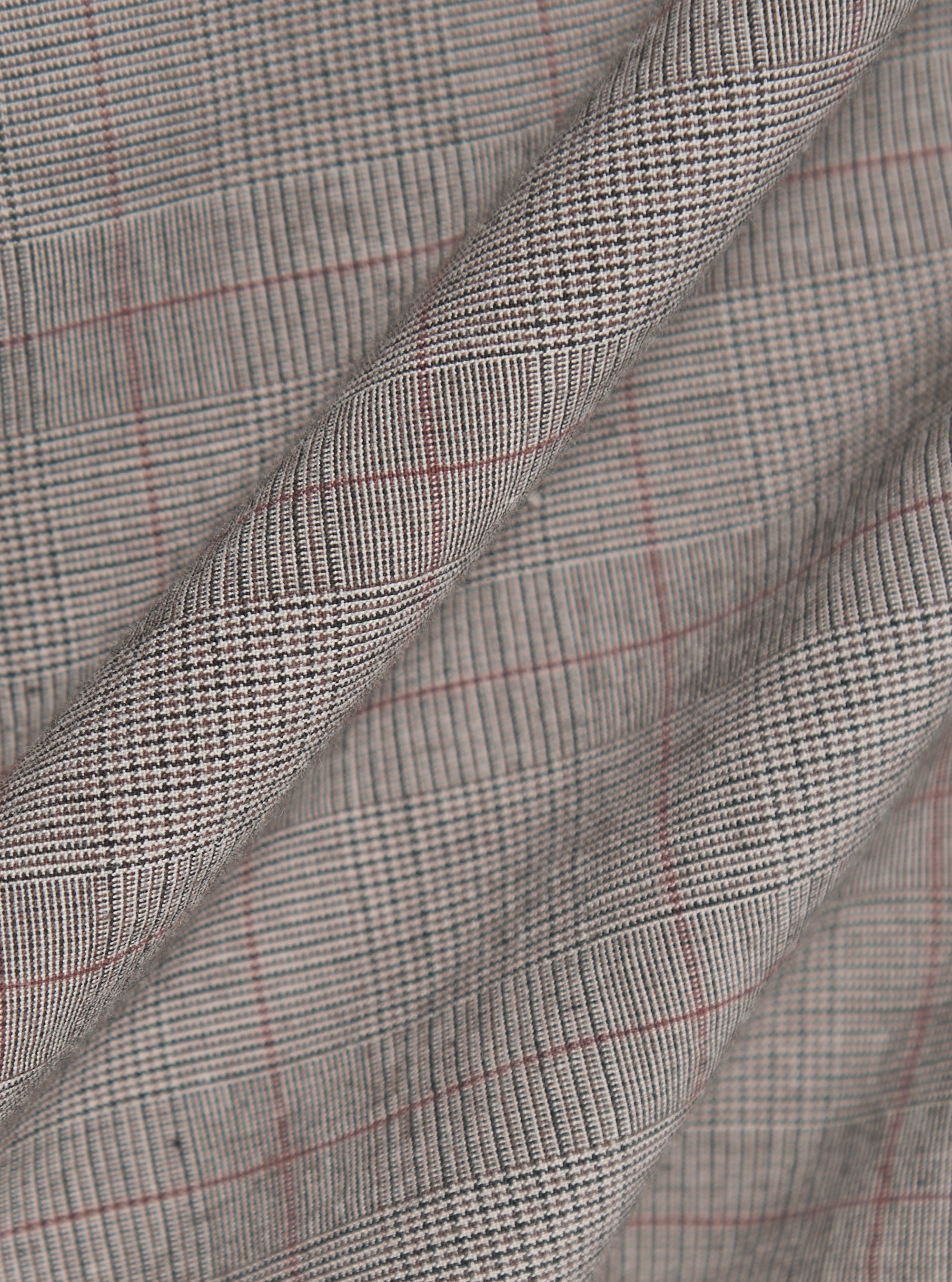 The Grey Brown Wales Glen Check Franck Jacket is shown in a detail view as a flat lay against a plain white background. The image highlights the intricate grey and brown glen check pattern of the cotton fabric and the construction of the garment's functional pockets and clean stitching.