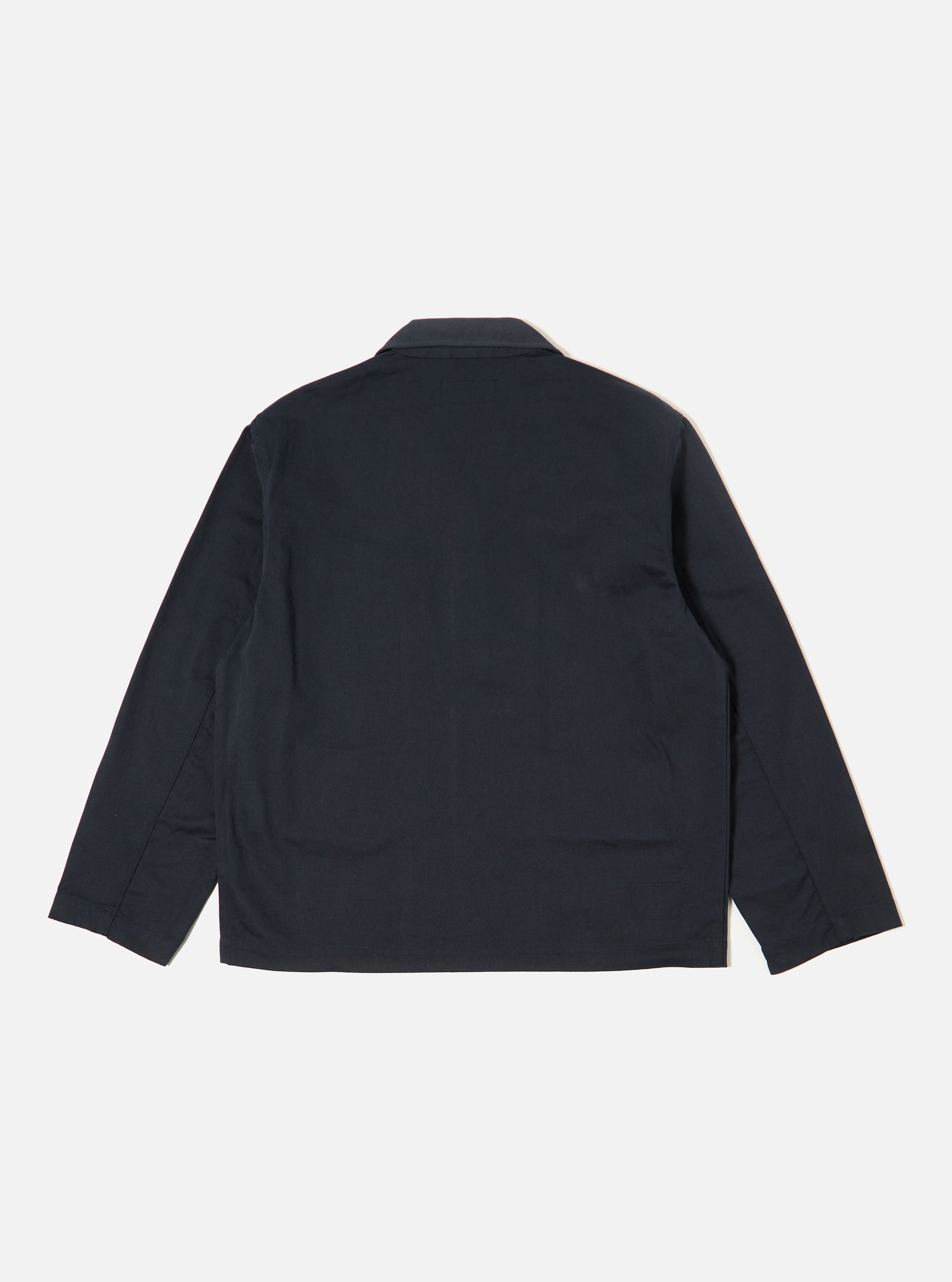The Navy Twill Franck Jacket is shown from the back as a flat lay against a plain white background. The image highlights the jacket's simple, clean construction, featuring a straight hem and a central vertical seam. The navy blue cotton twill fabric has a smooth, durable appearance.