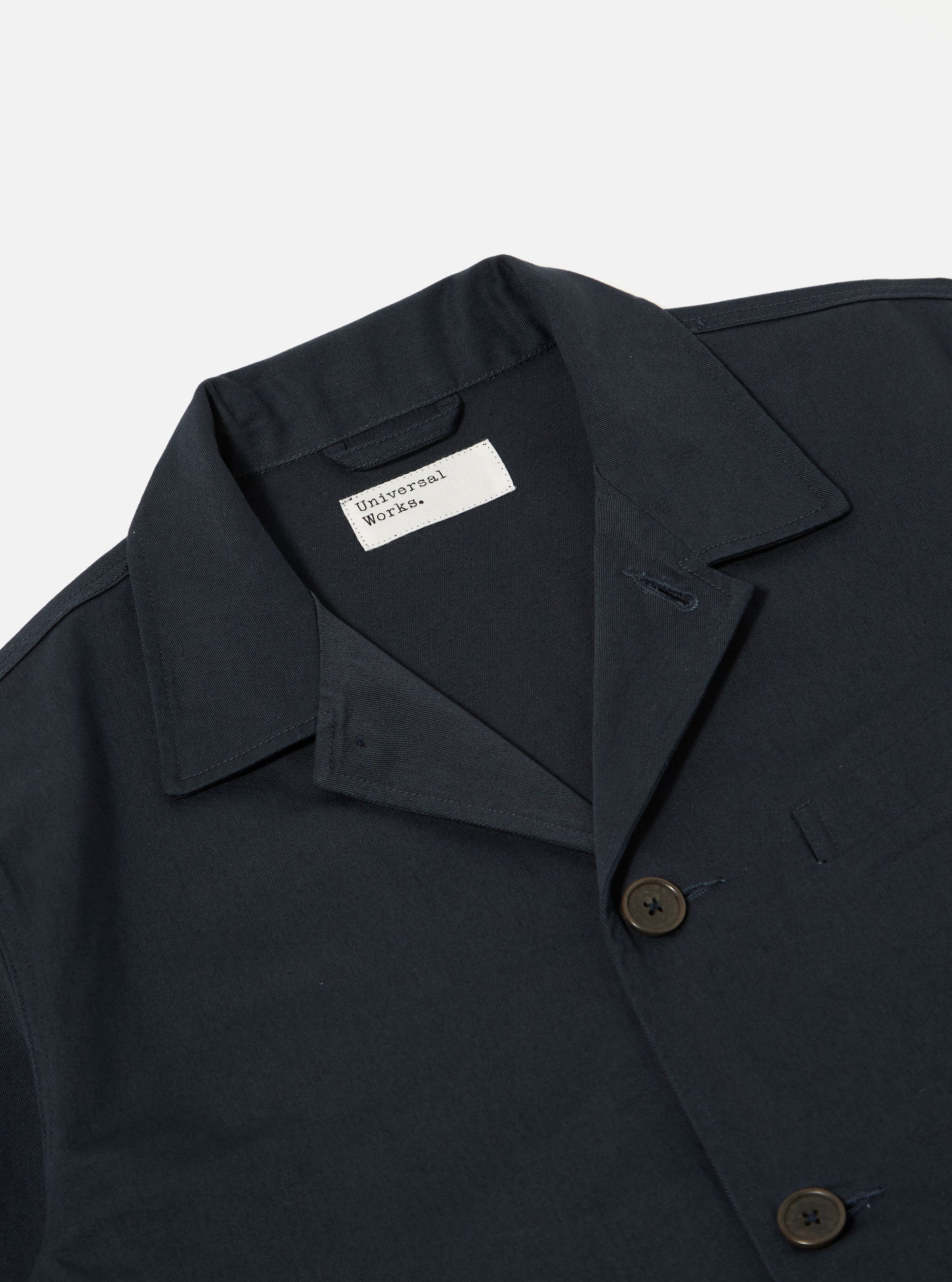 The Navy Twill Franck Jacket is shown from a rear angle as a flat lay against a plain white background. The image highlights the jacket's short cut, straight hem, and the clean construction of the back and sleeves. The navy blue cotton twill fabric has a smooth, durable appearance with visible stitching along the seams.