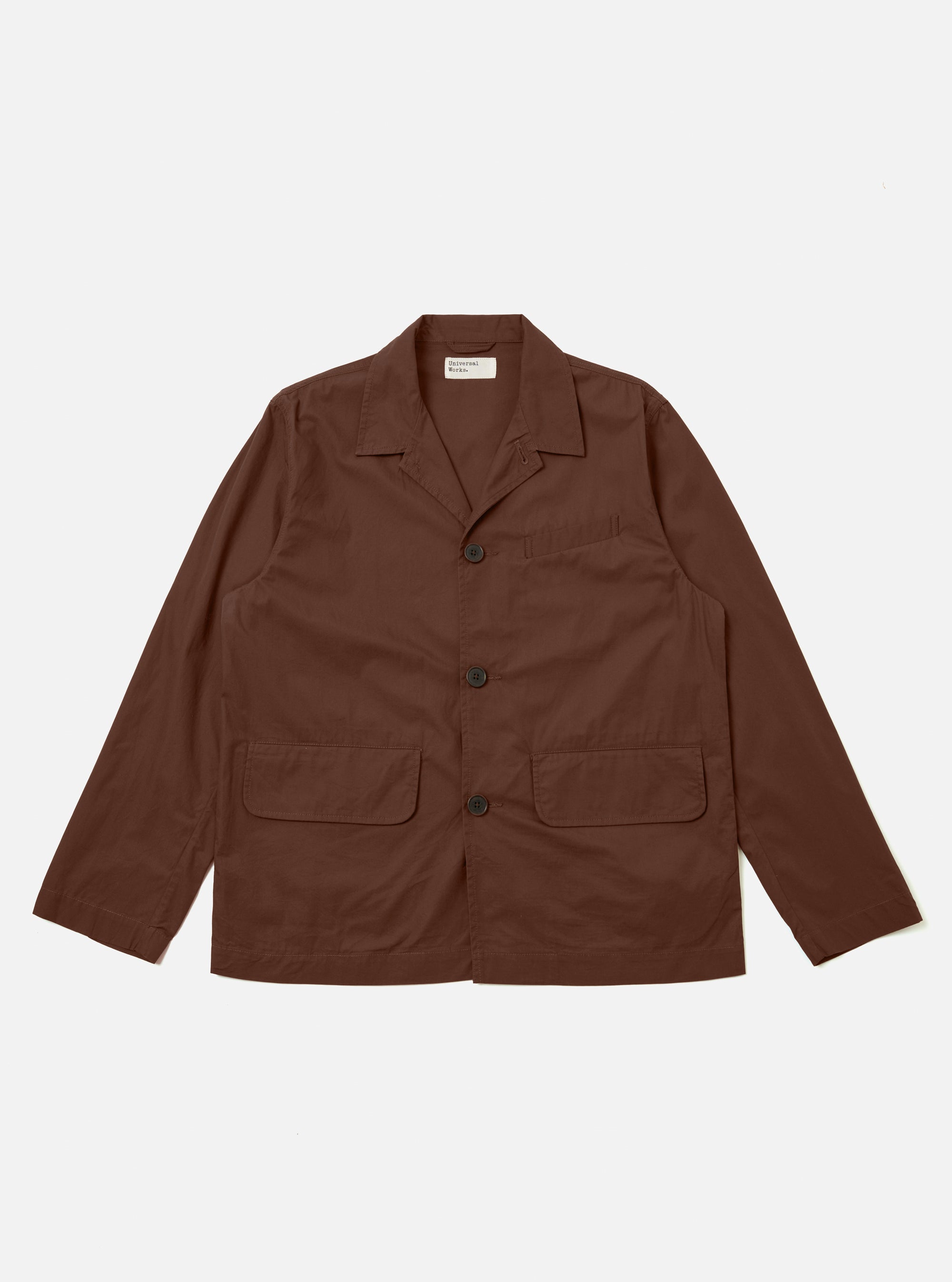 The Brown Peached Poplin Franck Jacket is shown as a flat lay against a white background. The jacket features a short, chore-style cut with a one-piece flat collar, two front flap pockets at the hips, and a single chest pocket. The smooth brown cotton poplin fabric is the primary focus.