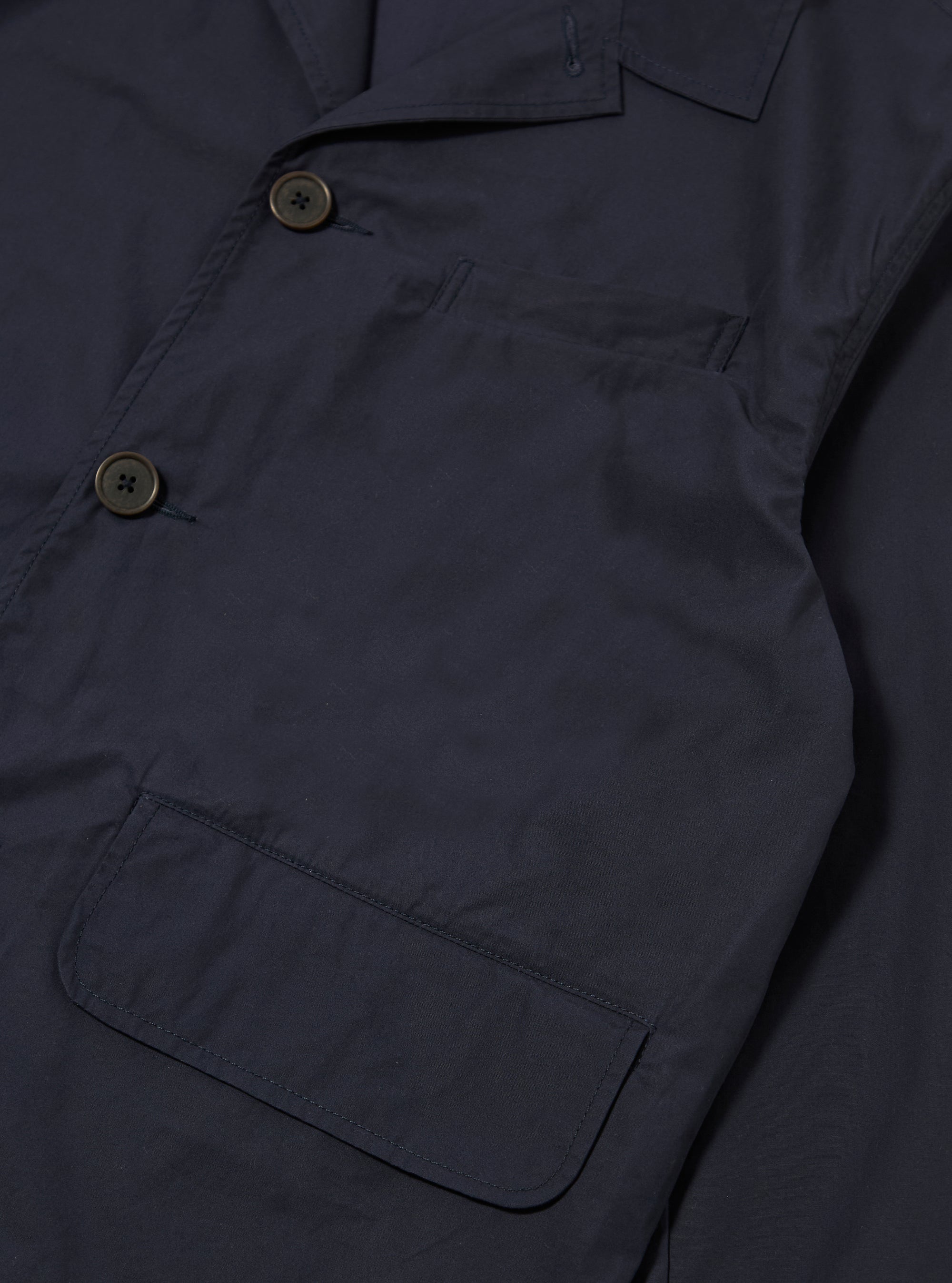The Navy Peached Poplin Franck Jacket is shown as a flat lay against a white background. The jacket features a short, chore-style cut with a one-piece flat collar, a five-button front closure, and three external pockets including one chest welt pocket and two lower flap pockets. The peached cotton fabric has a smooth, matte finish.