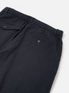The Dark Navy Ospina Cotton Pleated Track Pant is shown in a detail view as a flat lay against a plain white background. The image highlights the textured seersucker finish of the dark navy fabric and the construction of a functional rear patch pocket with a buttoned flap.