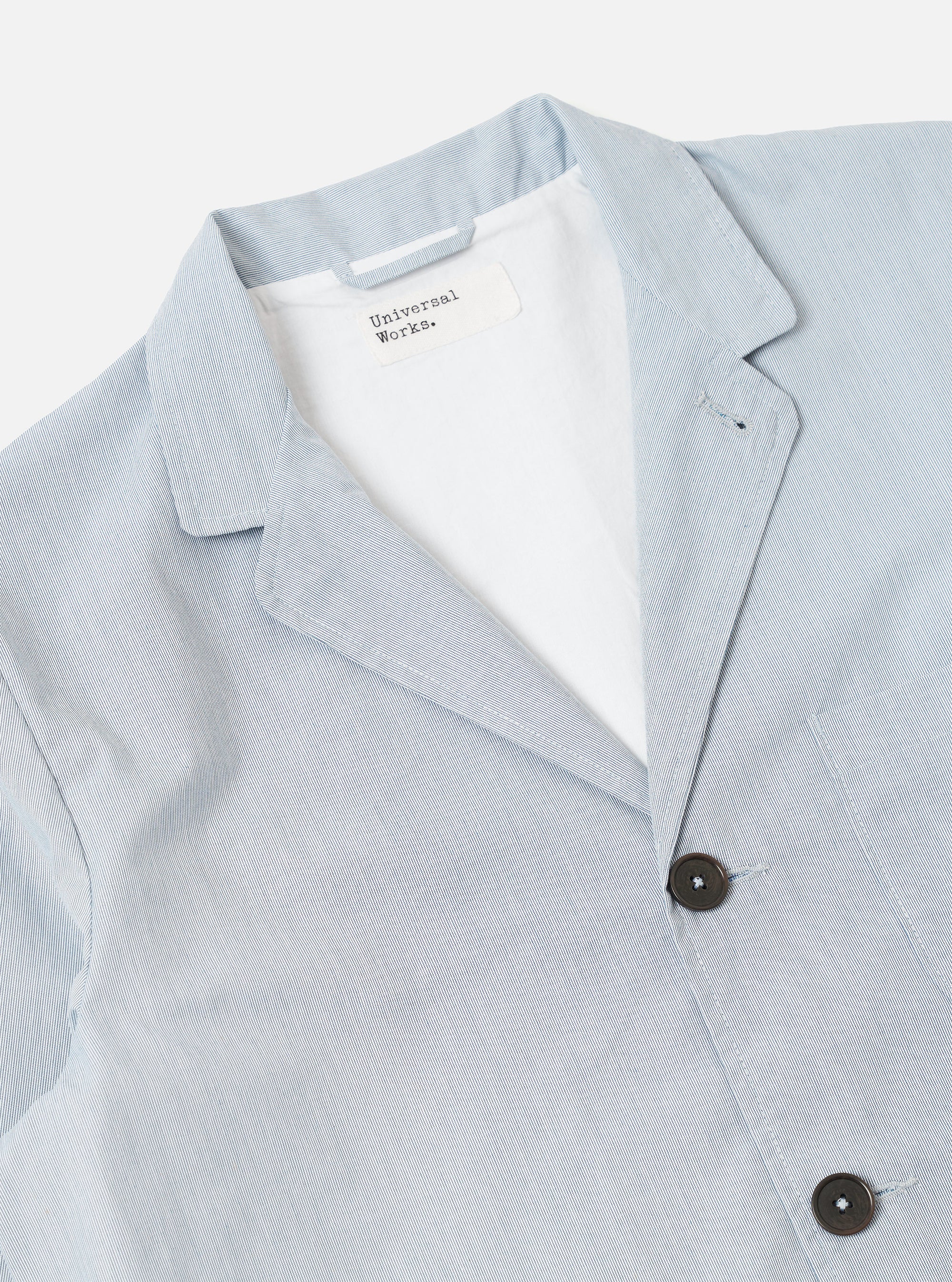The Navy Kennedy Stripe Three Button Jacket is shown from the back as a flat lay against a plain white background. The jacket features a vertical pinstripe pattern, a central rear vent, and structured shoulders. The navy cotton fabric has a crisp, tailored appearance.