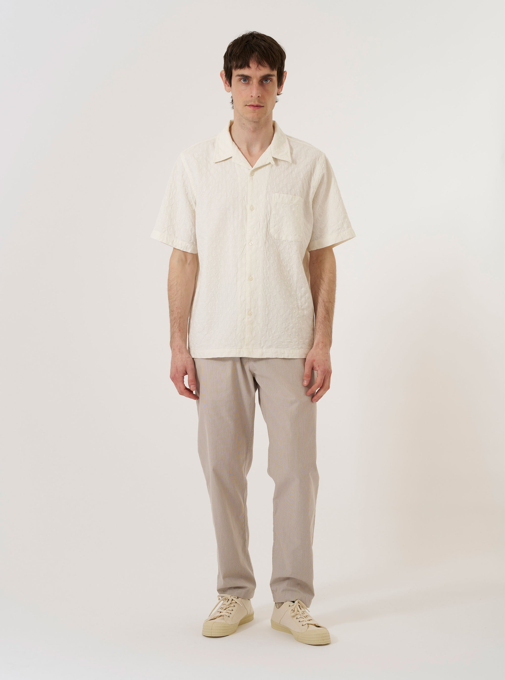The Brown Kennedy Stripe Military Chino is shown as a flat lay against a plain white background. The trousers feature a straight-leg silhouette with a vertical pinstripe pattern throughout. Prominent details include a button waist closure, belt loops, and two front slant pockets.
