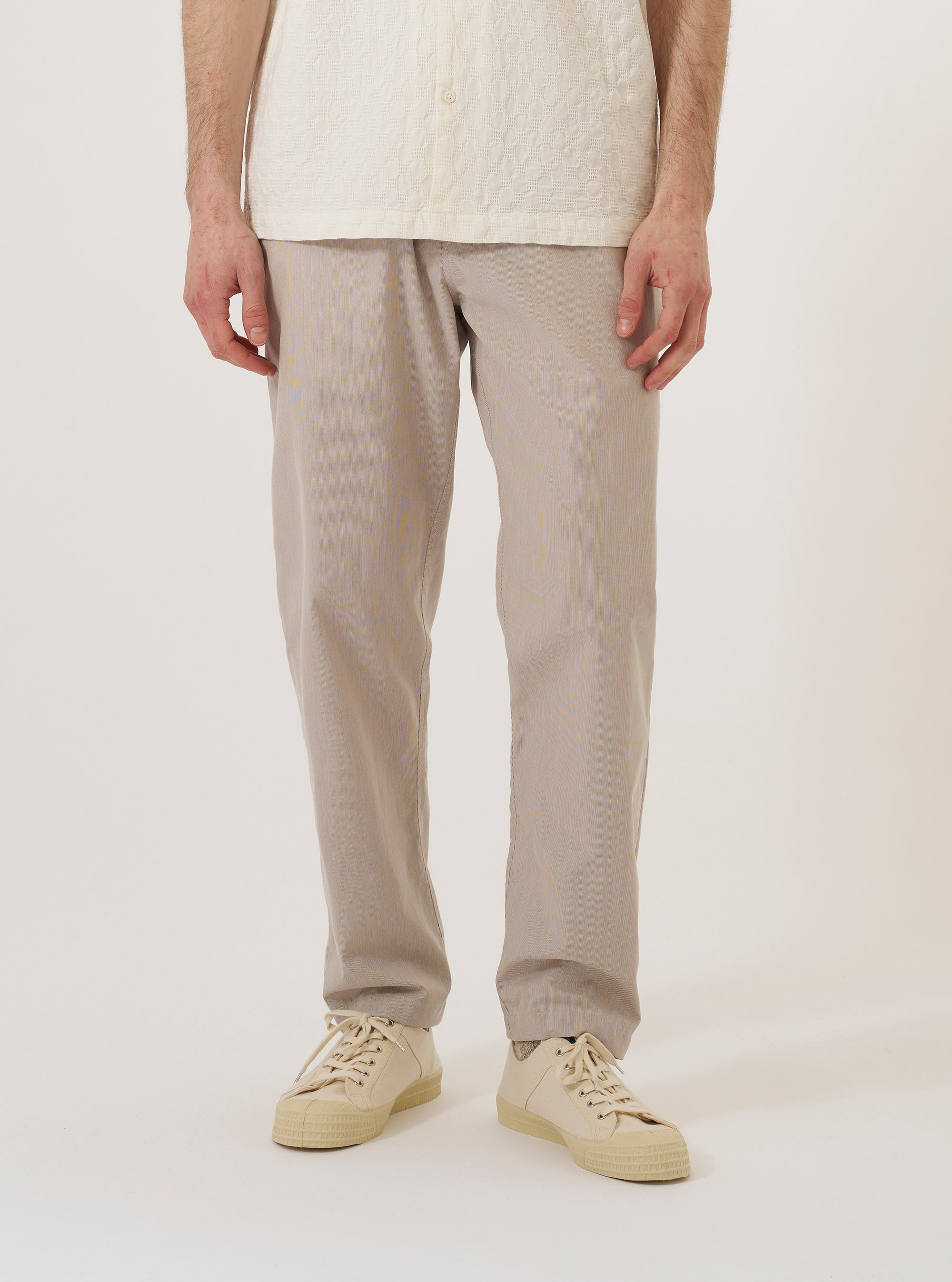 A model wears the Brown Kennedy Stripe Military Chino against a plain white background. The trousers feature a straight-leg fit and a distinct vertical stripe pattern in shades of brown. The model is shown from the waist down, paired with dark footwear, highlighting the chino's relaxed silhouette and classic workwear construction.