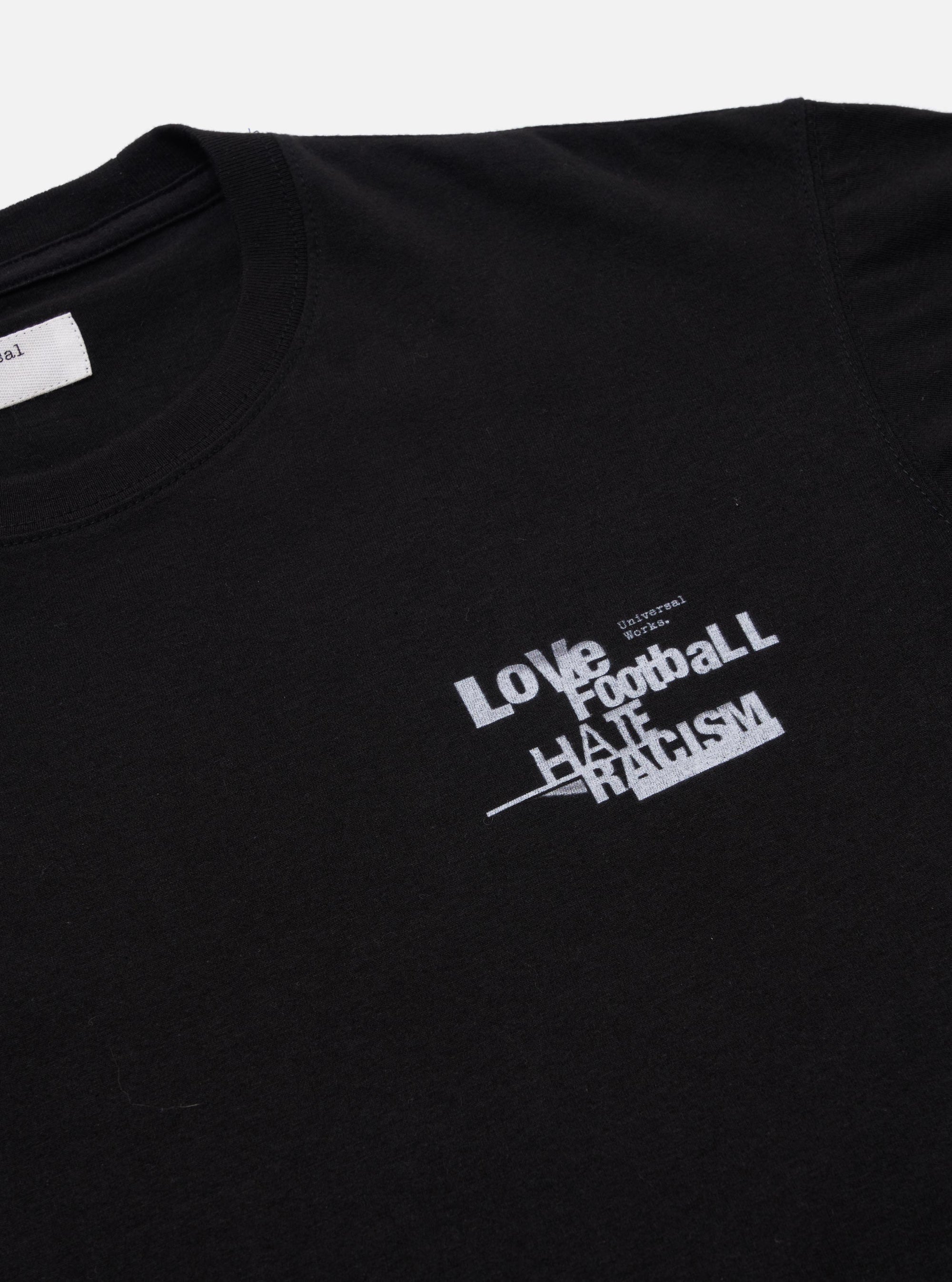 The Black Love Football Jersey Print Tee is shown from the back as a flat lay against a plain white background. The image highlights the clean construction of the rear panel, the short sleeves, and the ribbed crew neck. The garment is made from a solid black cotton jersey fabric.