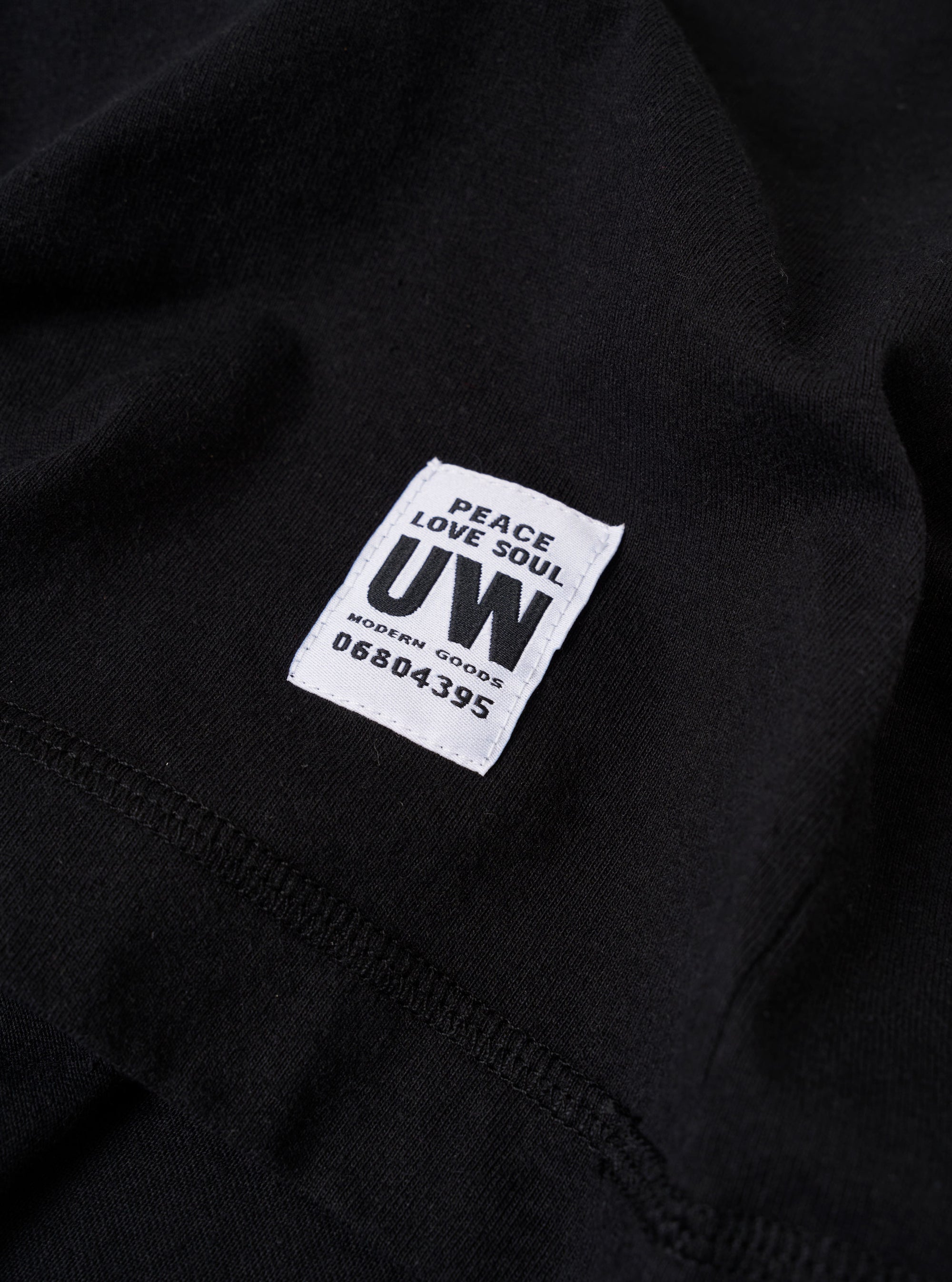 The Black Recycled/Bio Jersey Henry L/S Tee is shown from the back as a flat lay against a plain white background. The image highlights the clean construction of the shoulders and the straight hem of the long-sleeved garment. The black jersey fabric appears smooth and consistent throughout.