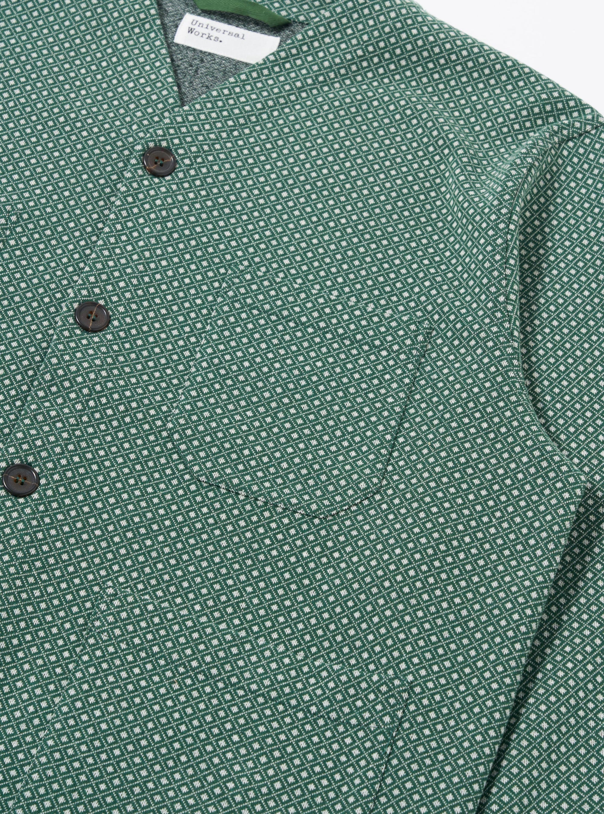 The Green Argyll Jersey Cardigan is shown from a rear angle as a flat lay against a plain white background. The image highlights the all-over green and dark-toned argyle pattern and the simple, straight-cut construction of the back panel. The cardigan features ribbed detailing at the hem and cuffs.